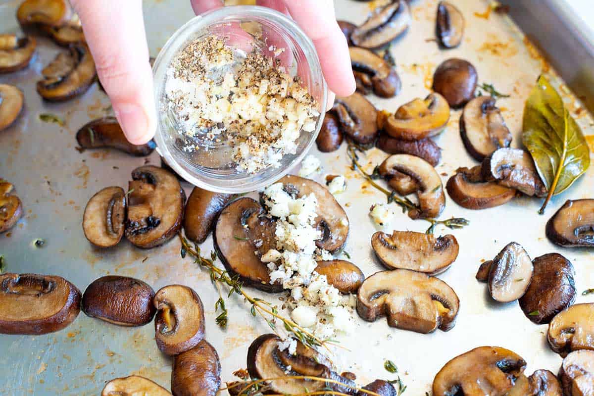 How to roast mushrooms: Adding garlic, salt and pepper to the mushrooms 