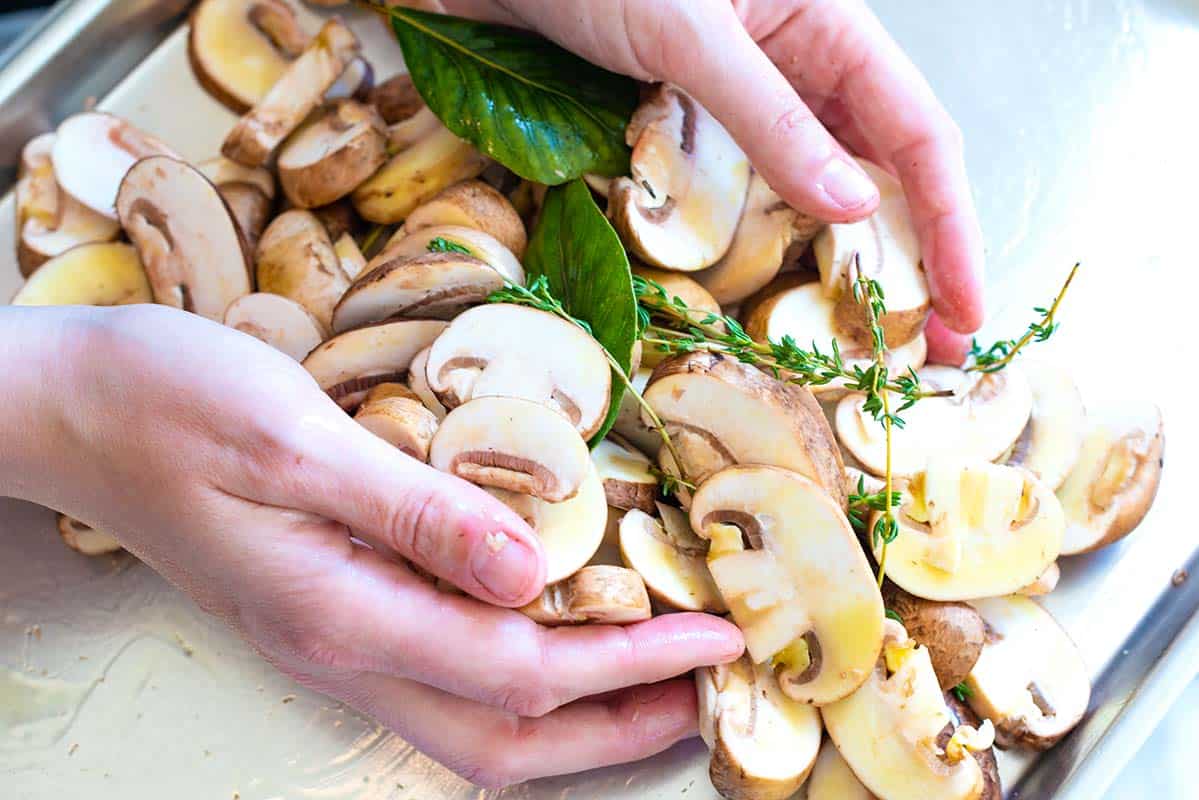 Getting the mushrooms ready for roasting - Tossing the mushrooms with fresh herbs, olive oil, garlic, salt and pepper.