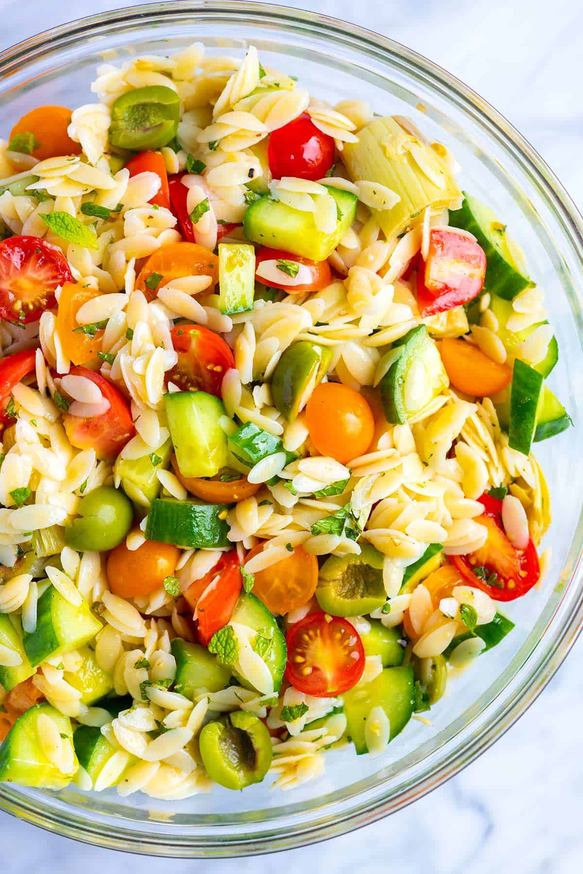 Everyone loves this easy orzo pasta salad recipe with a simple lemon vinaigrette, cucumber, olives, tomato and fresh herbs.