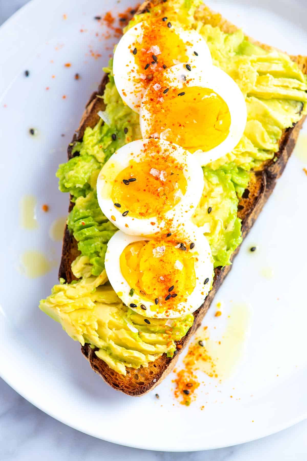 A slice of toast with smashed avocado, spices, and hard boiled egg.