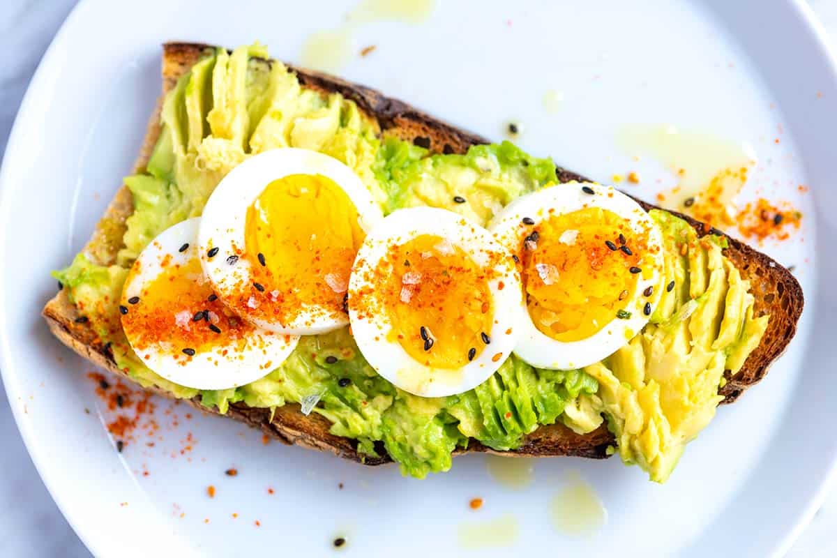 Avocado toast with hard-boiled egg and seasoning on sourdough bread.