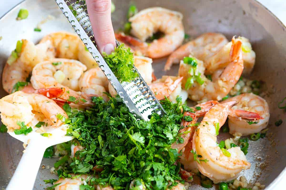How to make cilantro lime shrimp - adding cilantro and the zest and juice of a lime to the shrimp