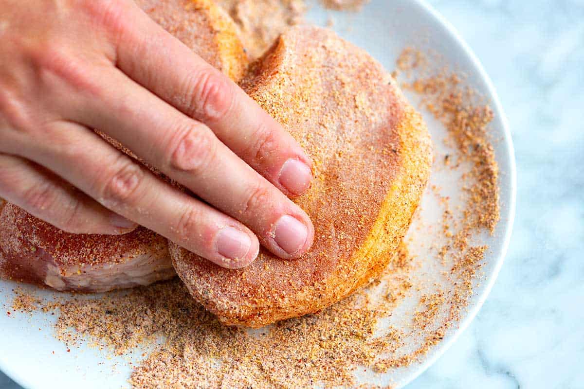 Rubbing pork chops with spice rub