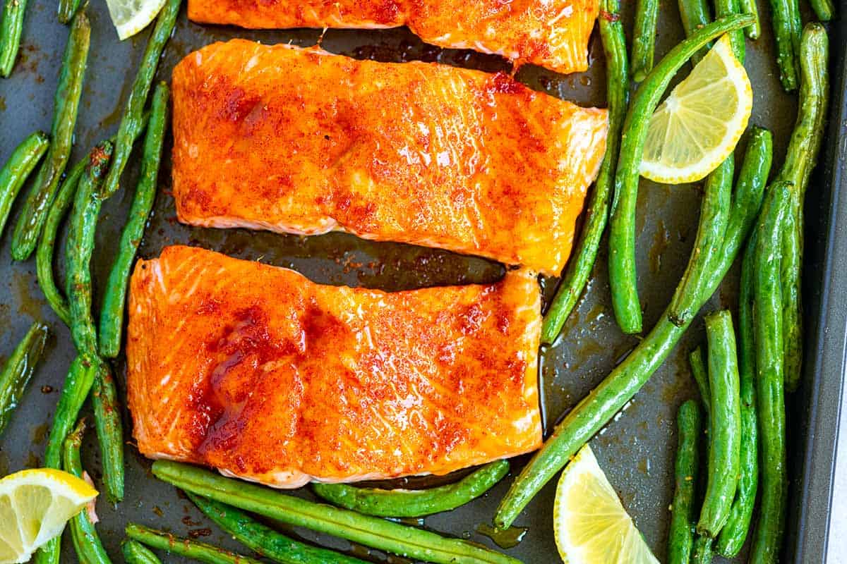 Brown sugar baked salmon on a baking sheet with green beans