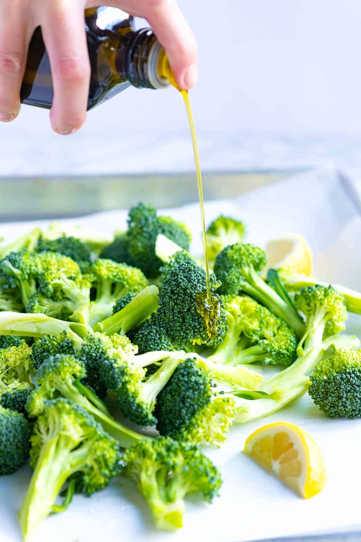 How to Make Roasted Broccoli: Adding olive oil to raw broccoli before roasting