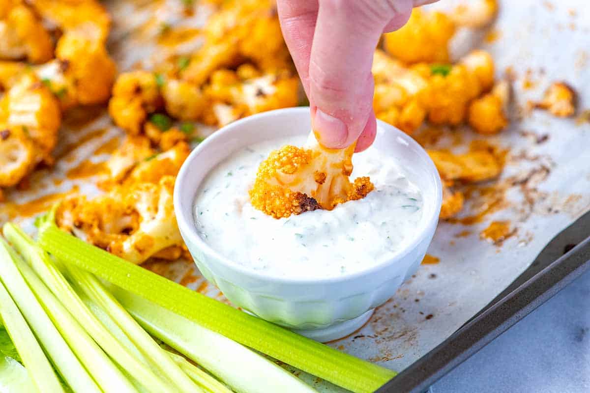 Dipping a buffalo cauliflower wing into blue cheese dressing