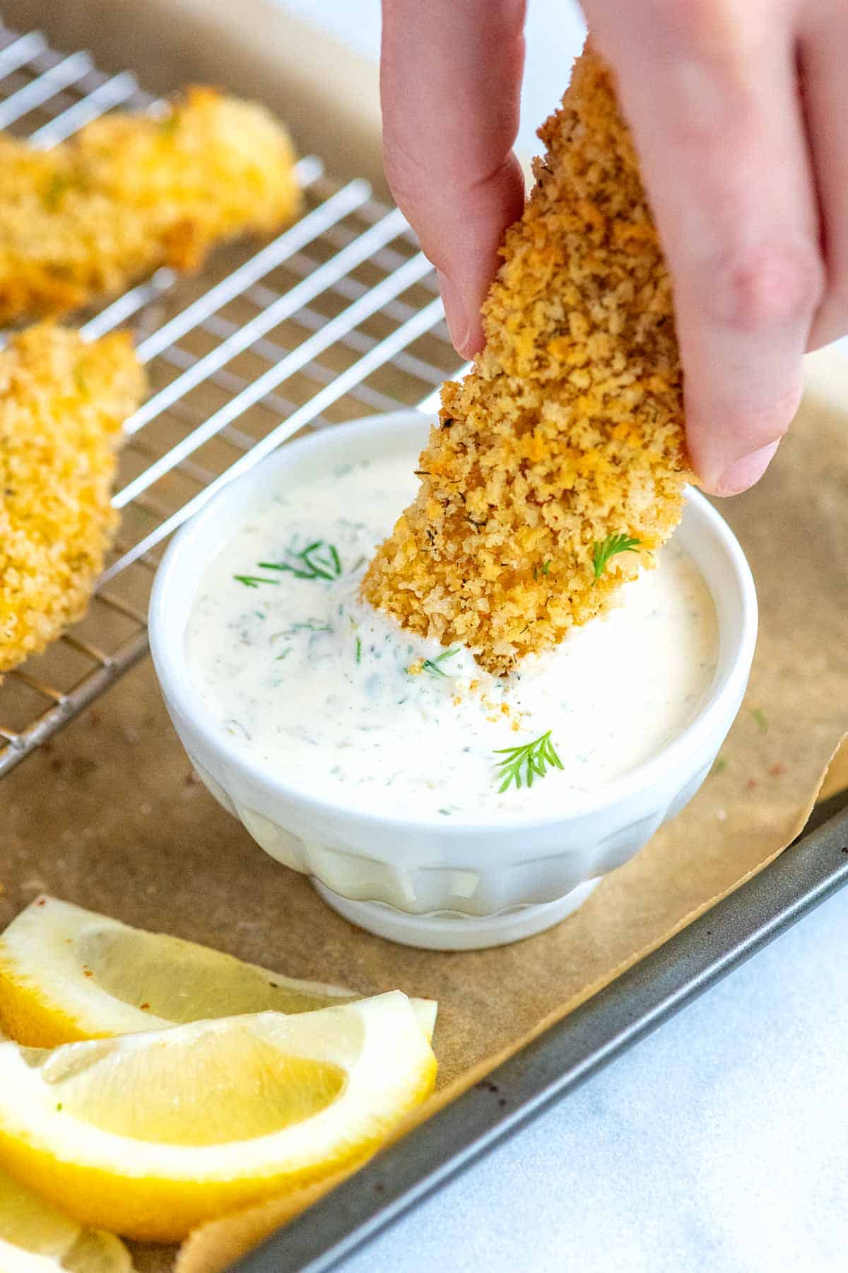 Dipping homemade fish sticks into tartar sauce