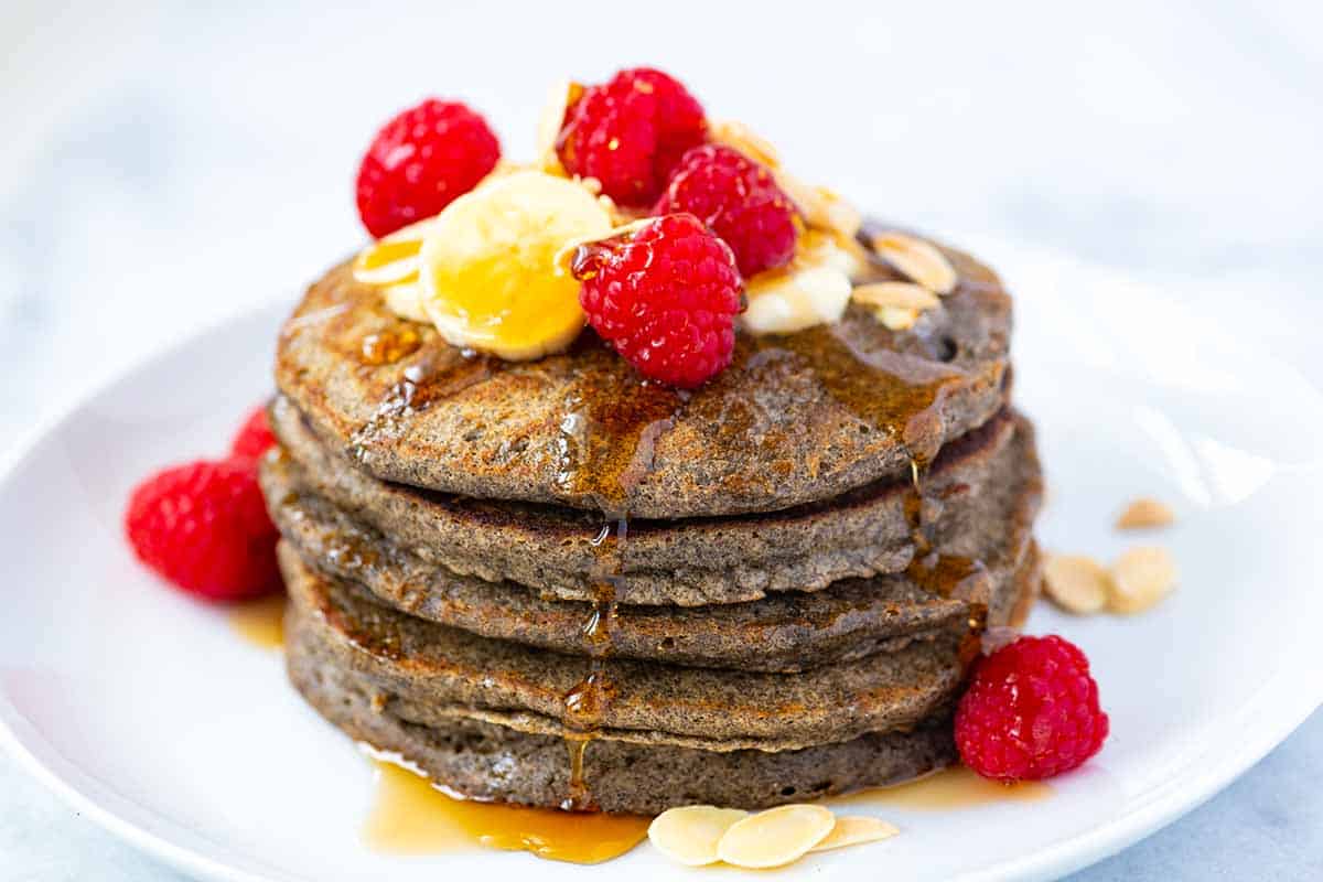 A stack of Buckwheat Pancakes with sliced bananas and raspberries