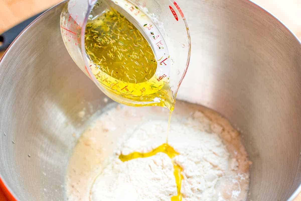 Infused garlic herb olive oil being added to focaccia dough