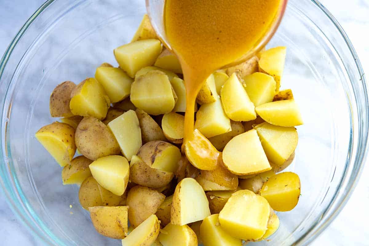 Add olive oil dressing to warm potatoes