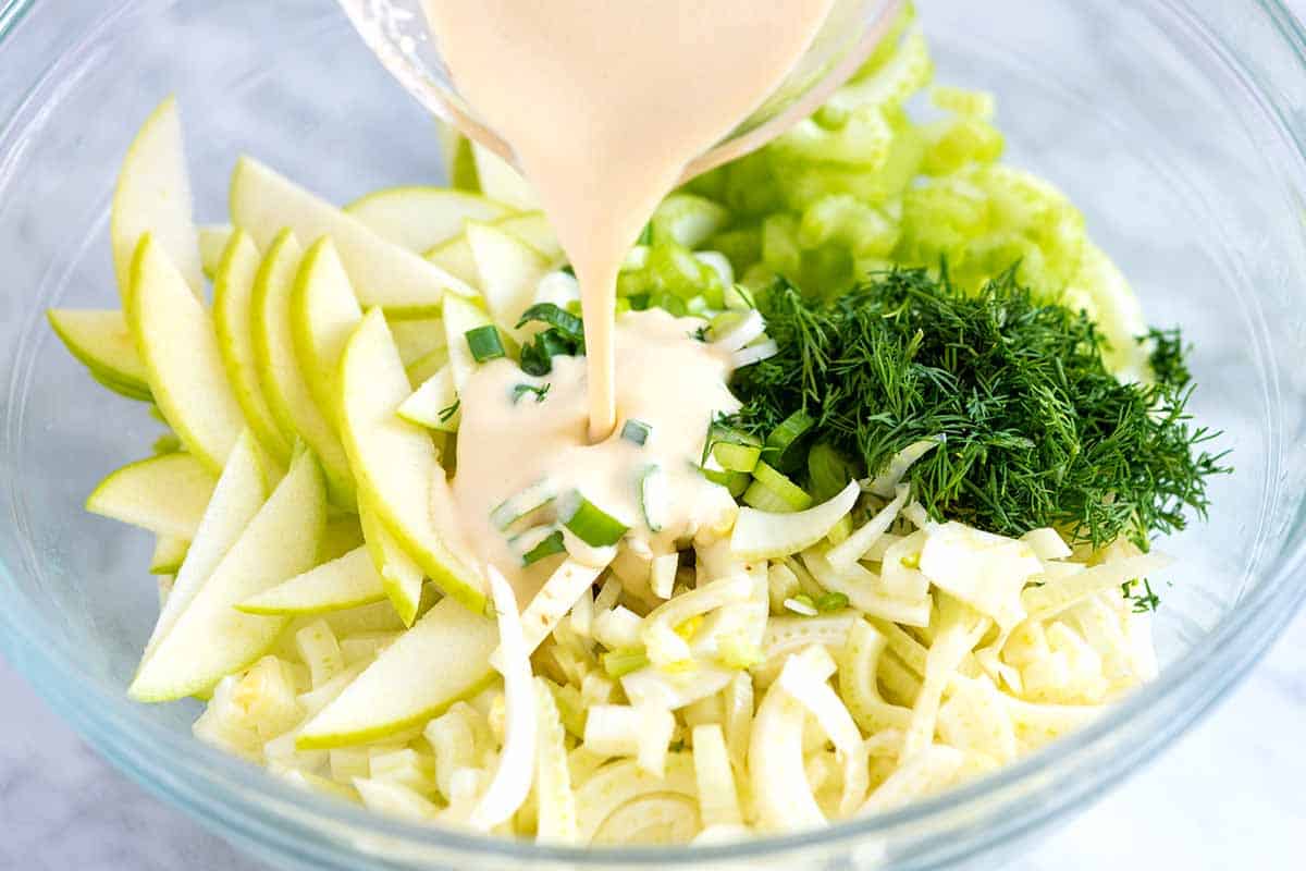 How to make apple salad: Add dressing to apples, celery and fennel.