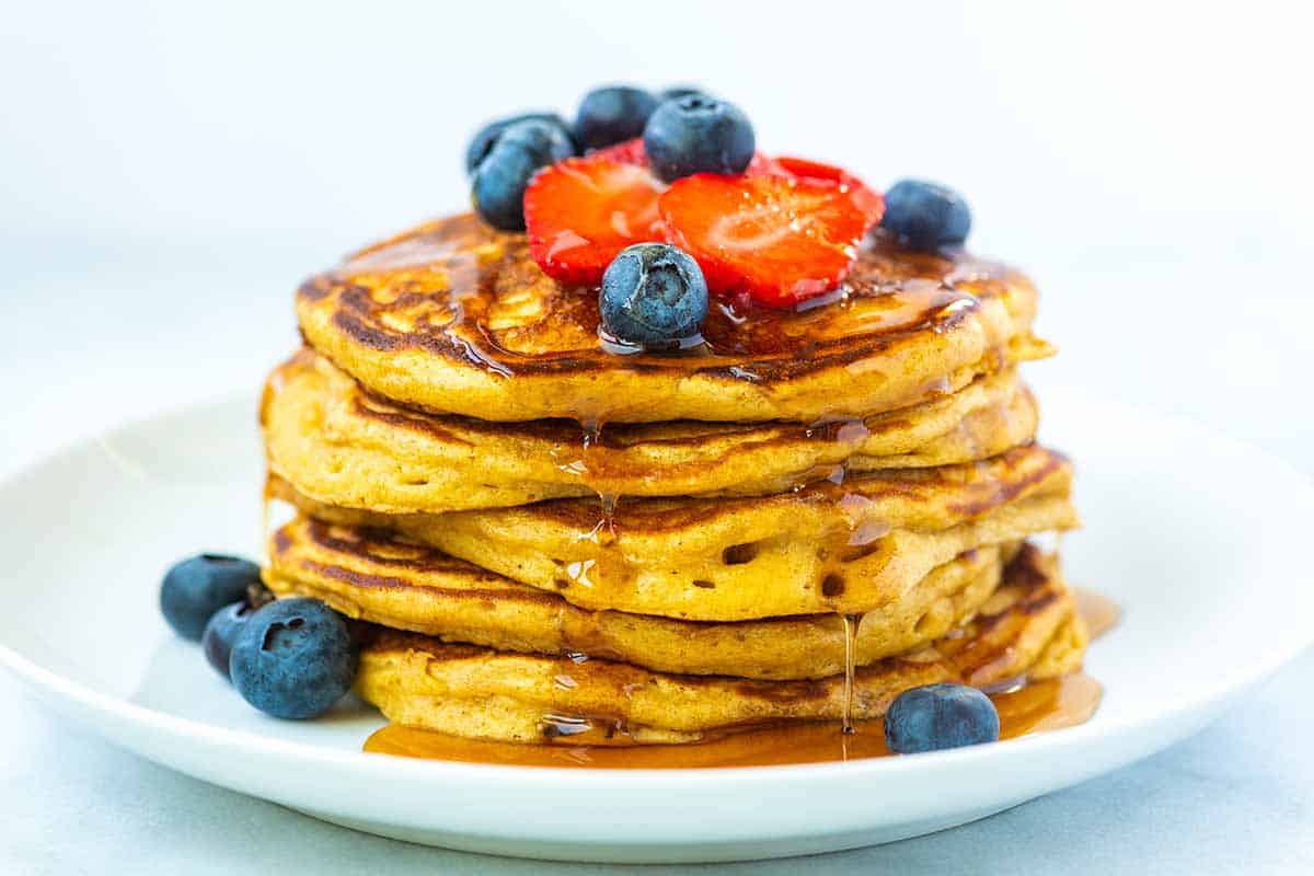 Stack of fluffy buttermilk pancakes with syrup and berries