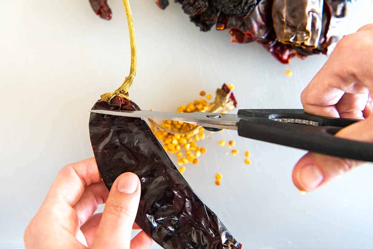 Removing the stem and seeds from peppers for enchilada sauce