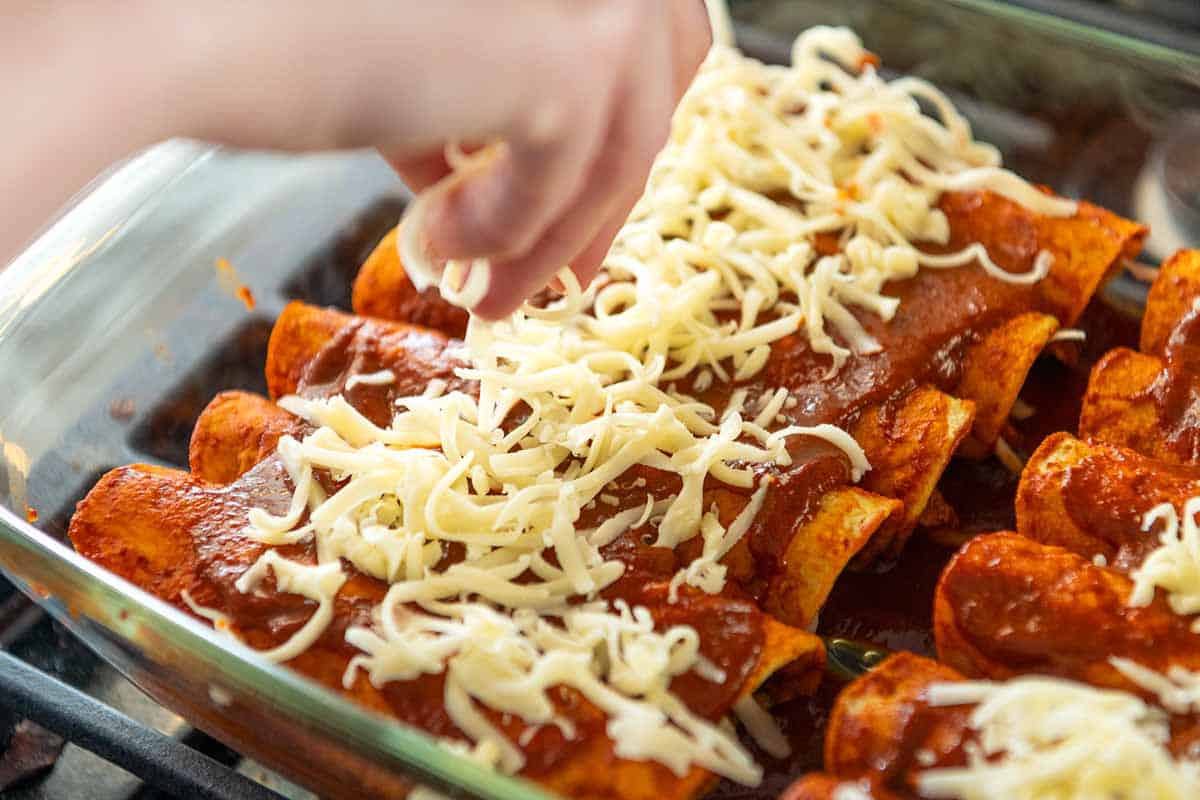 Adding cheese to chicken enchiladas before baking