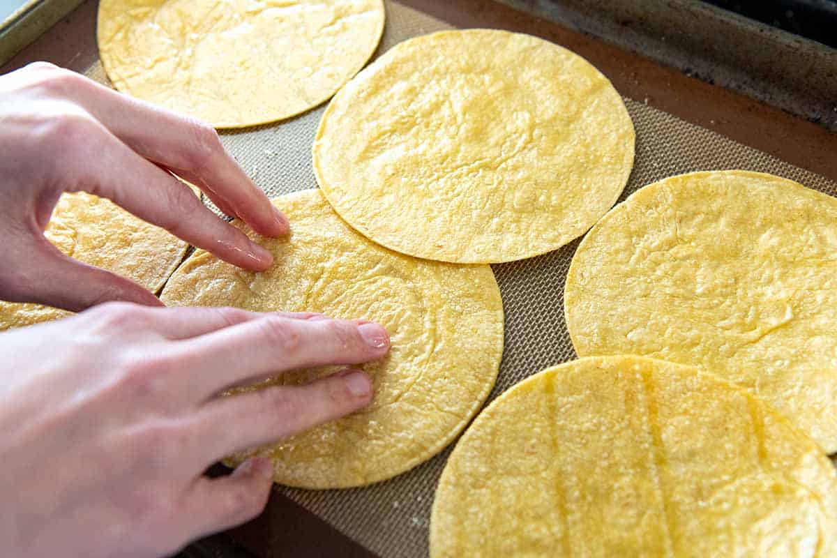 Rubbing oil over corn tortillas for enchiladas