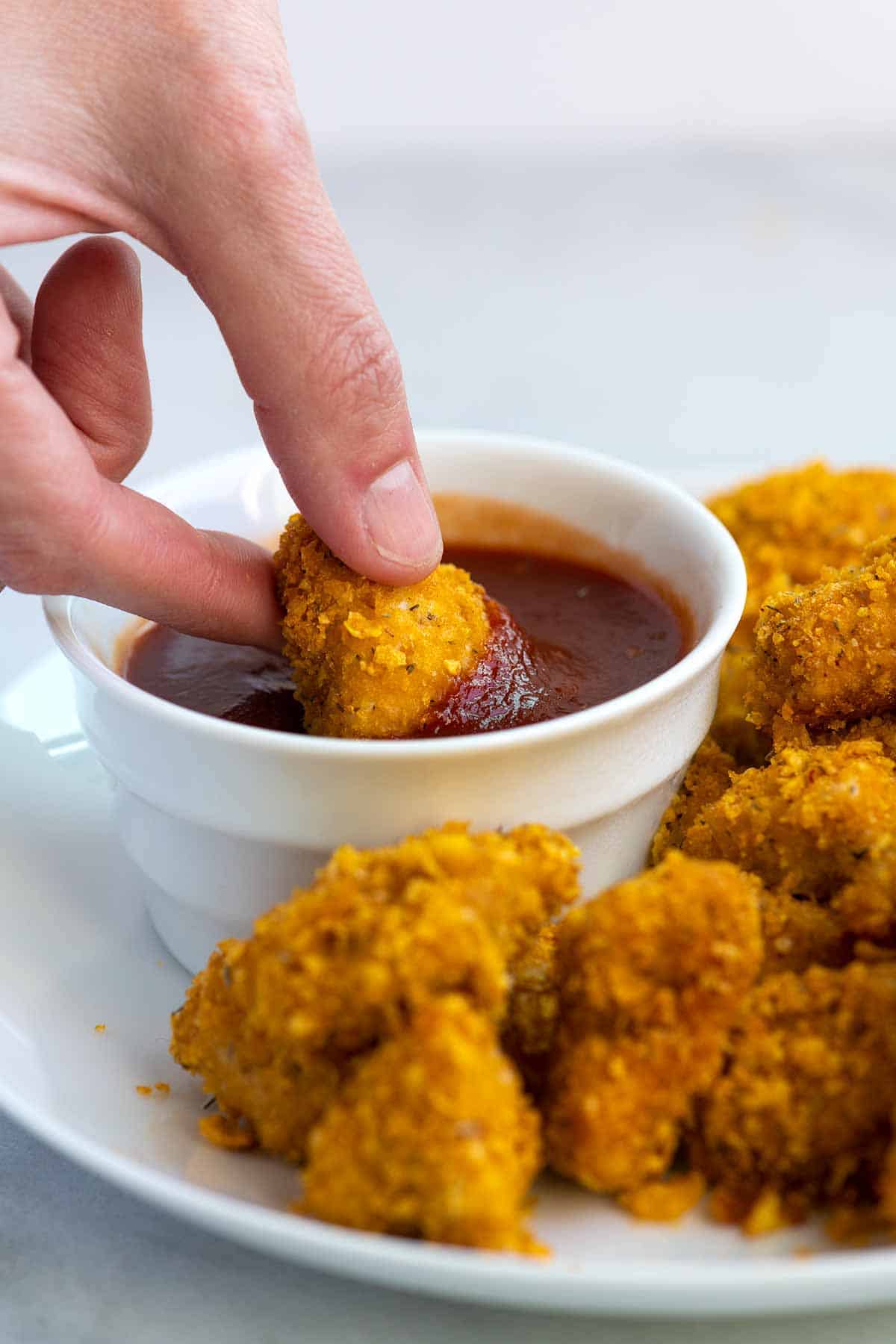 Dipping popcorn chicken into ketchup