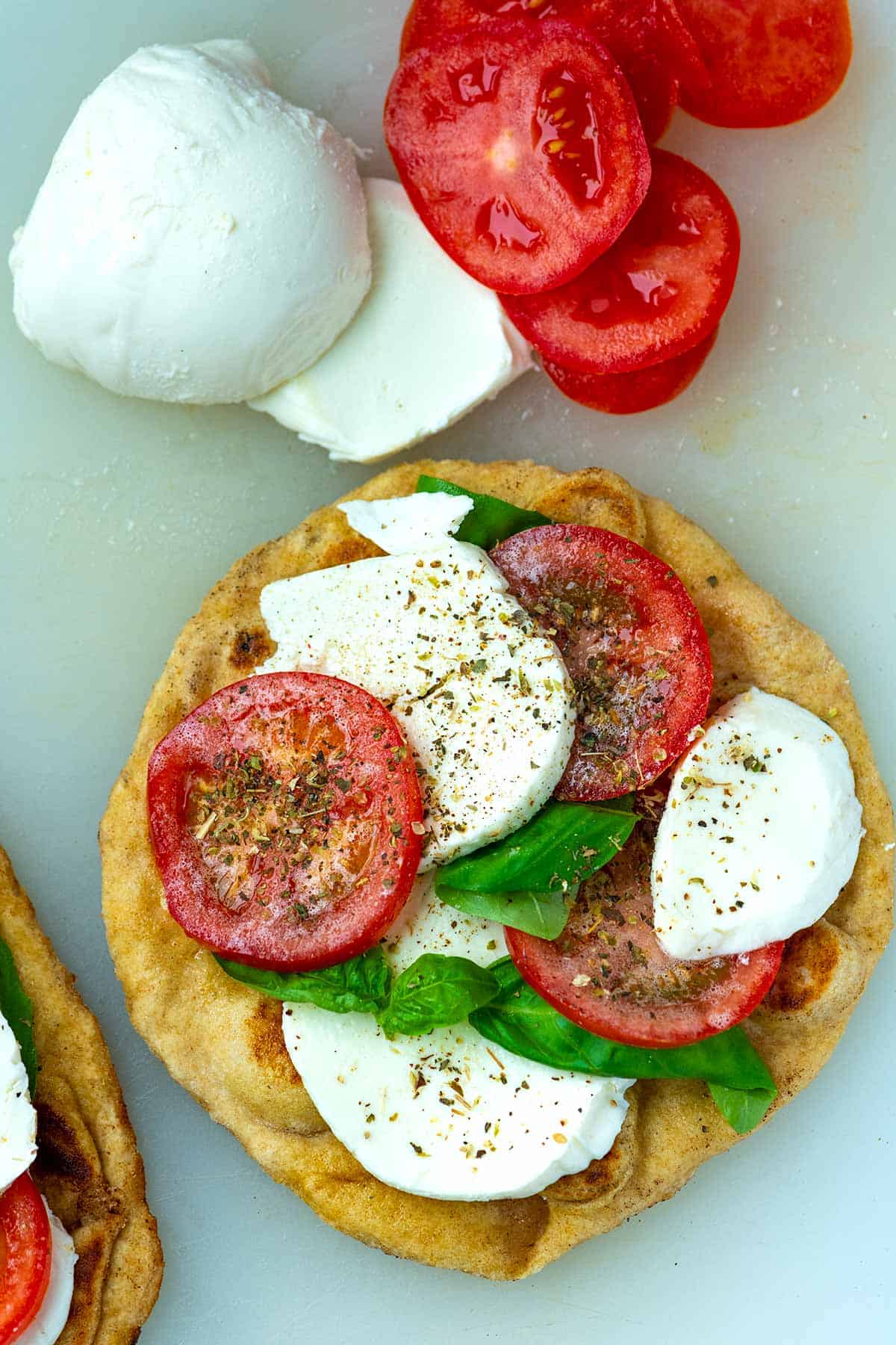 Prepping pizza made with flatbread, sliced tomatoes and sliced mozzarella