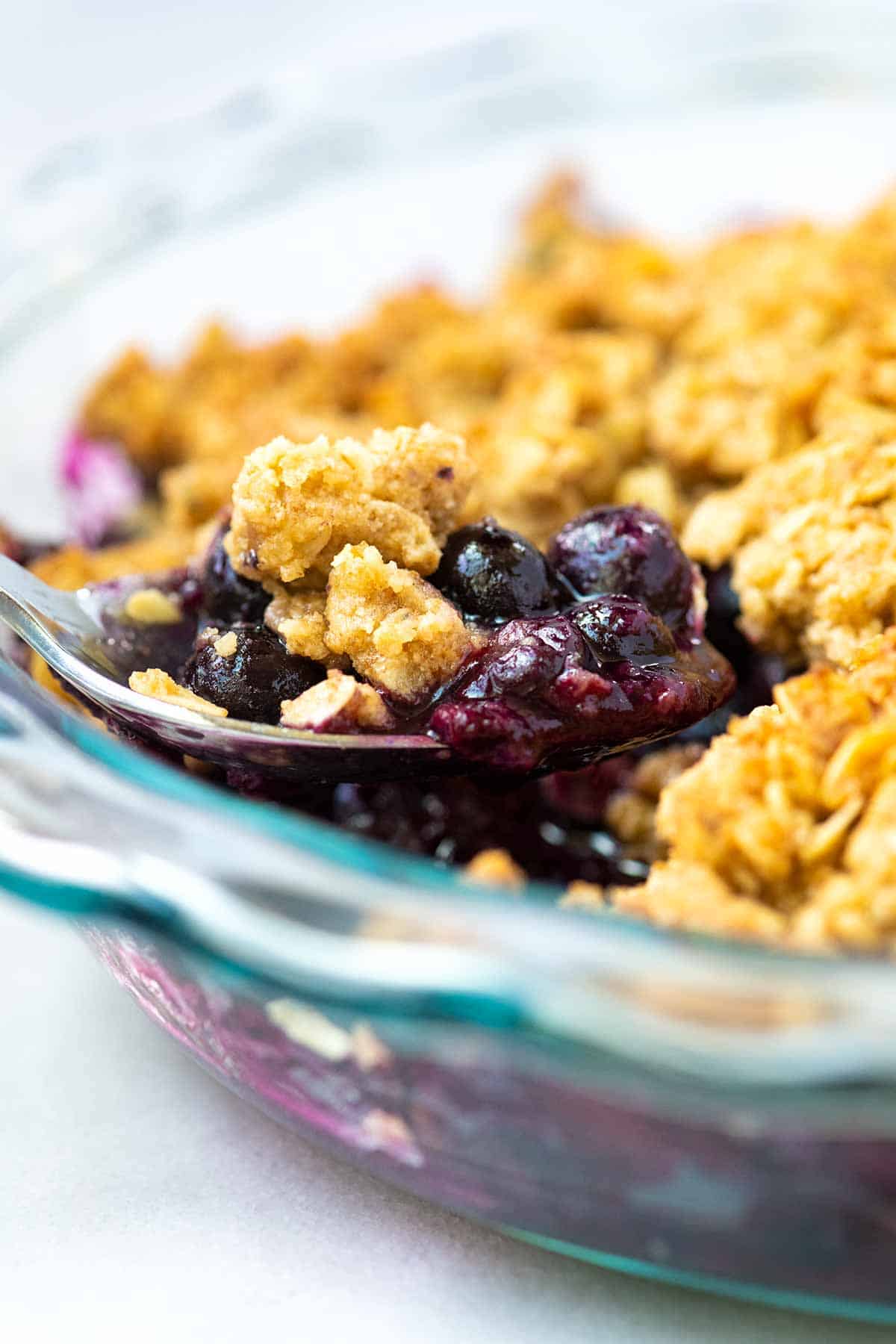 Scooping out a serving of baked blueberry crumble.