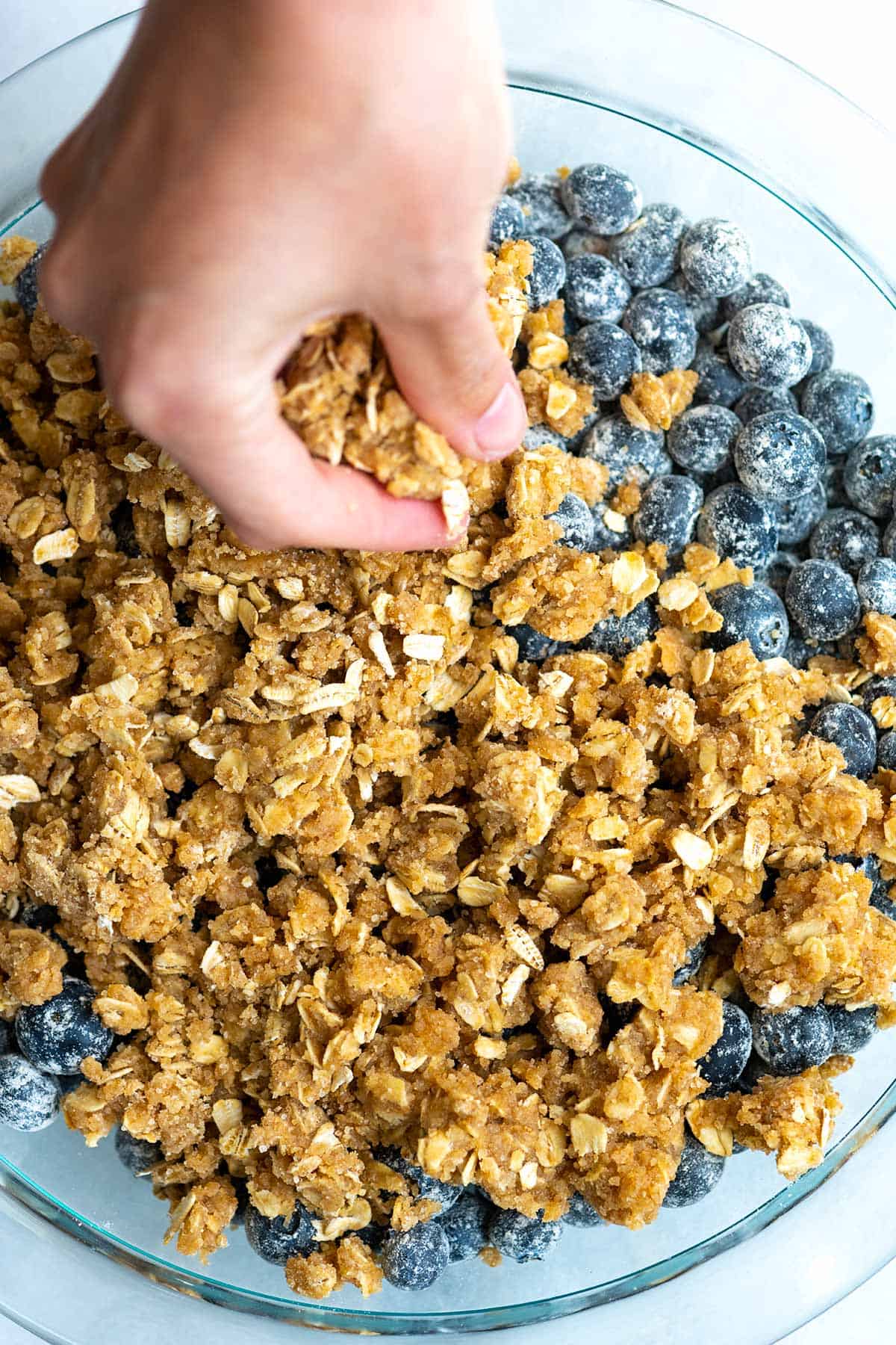 Adding crumble topping to blueberries.