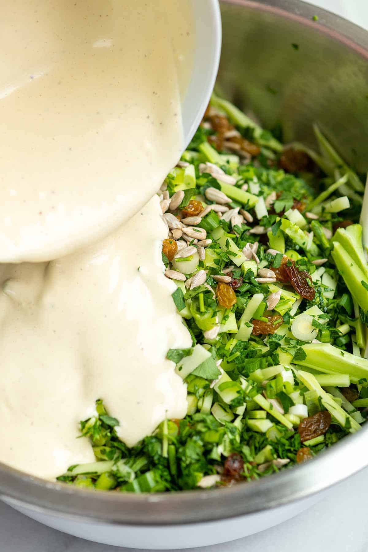 Adding a creamy broccoli slaw dressing to broccoli slaw ingredients