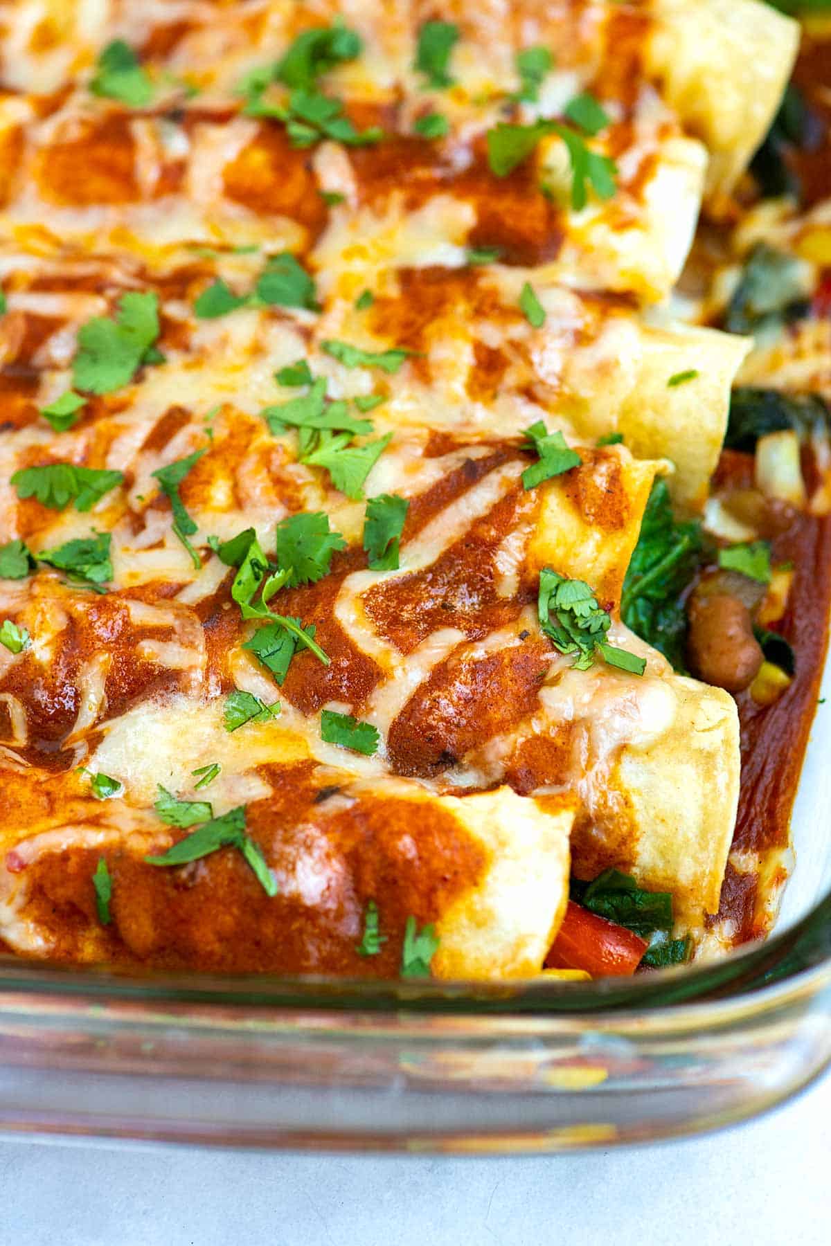 Vegetable and bean enchiladas lined up in a baking dish