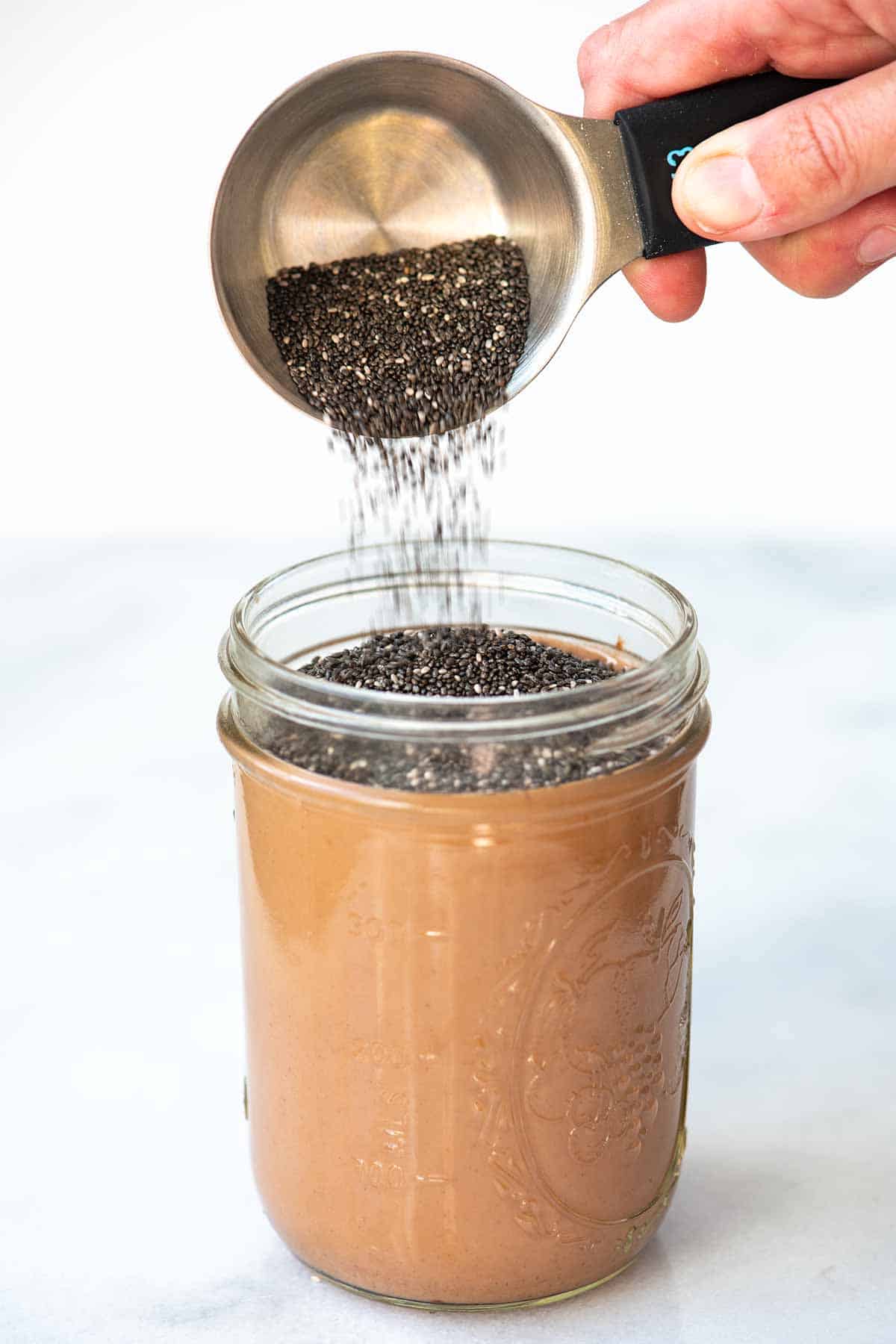 Adding chis seeds to the chocolate milk to make chia pudding