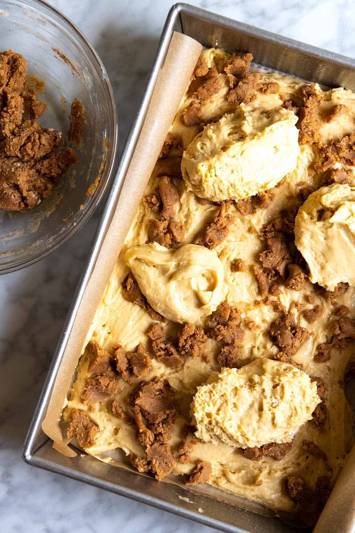 How to Make Cinnamon Coffee Cake: Adding coffee cake batter to the pan with cinnamon streusel