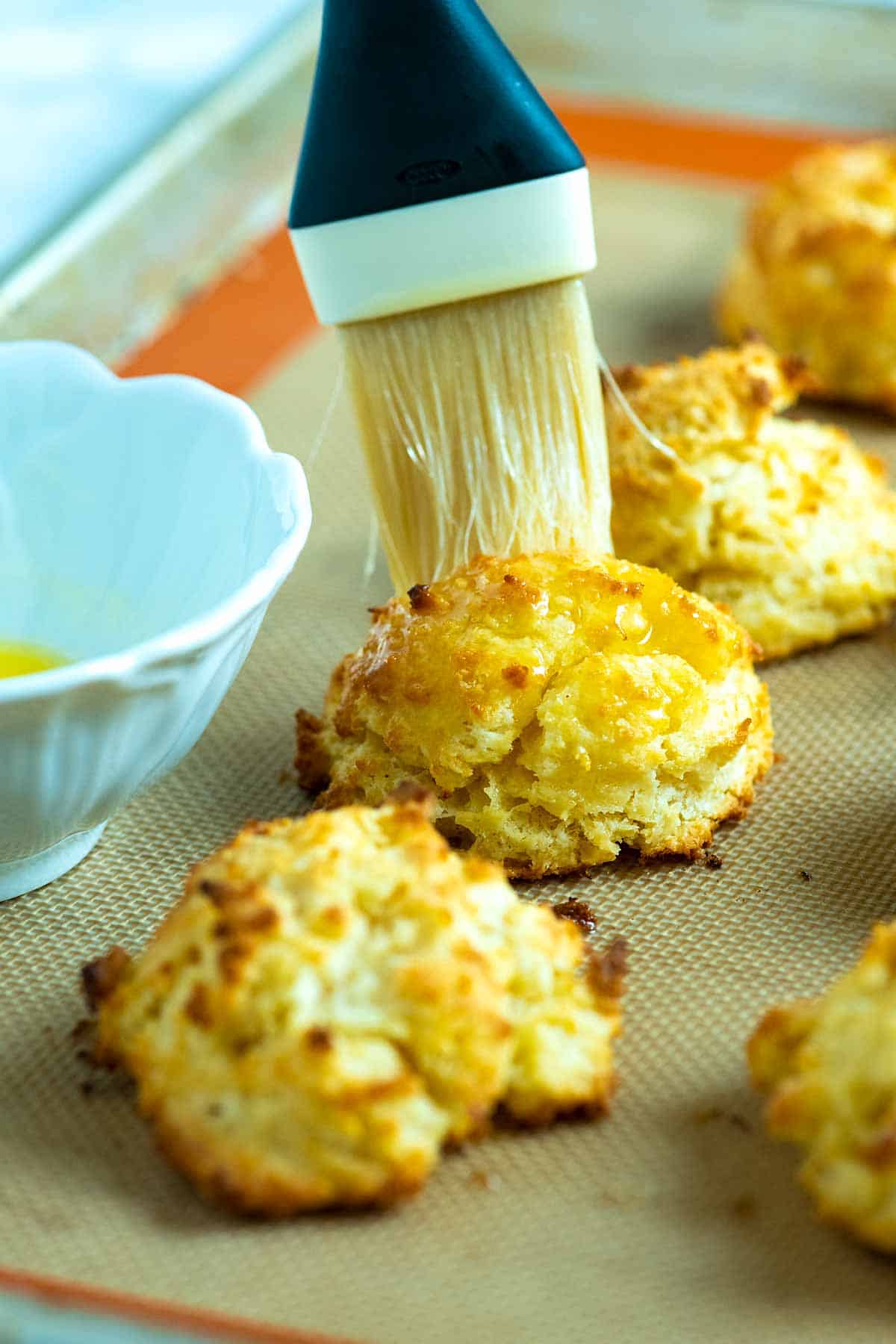 Brushing melted butter onto homemade drop biscuits