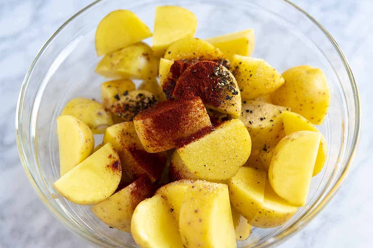 Seasoning potatoes before they go into the oven.