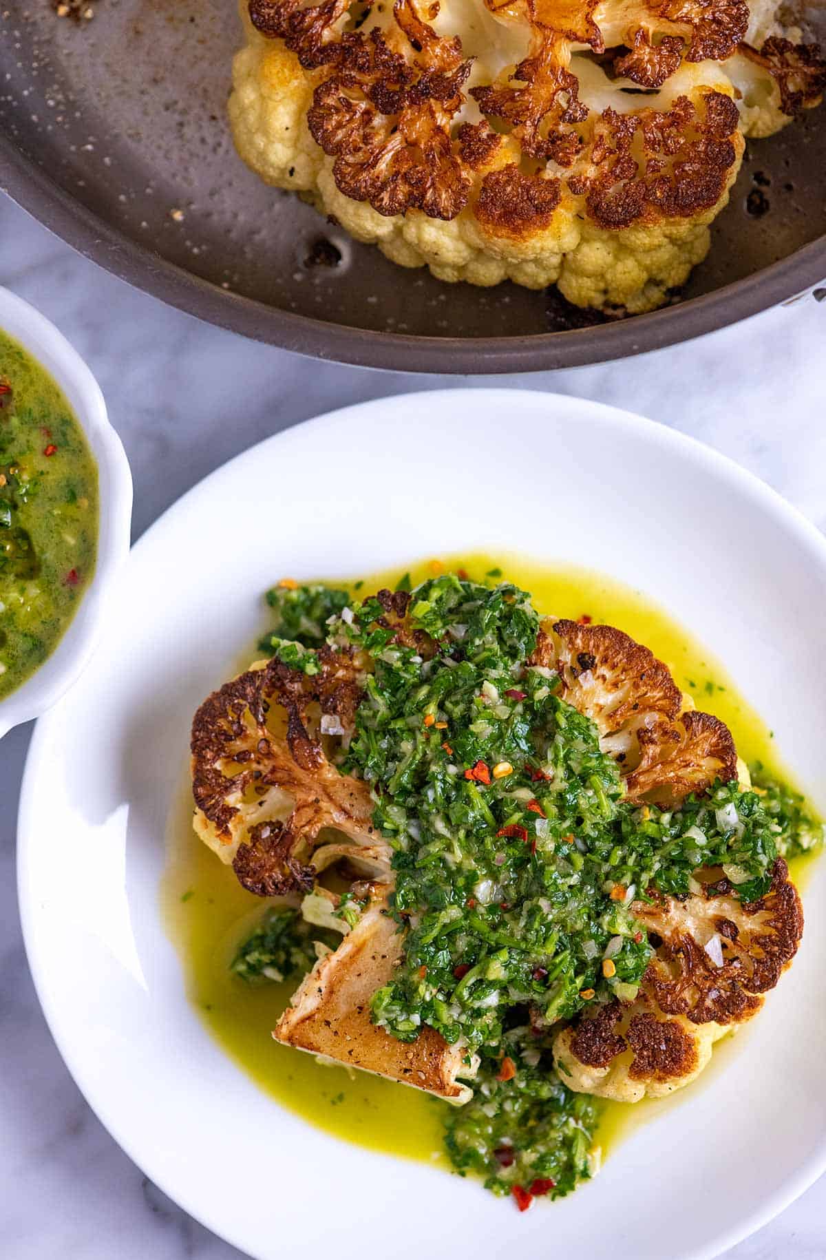 Roasted cauliflower steaks with chimichurri sauce spooned over the top