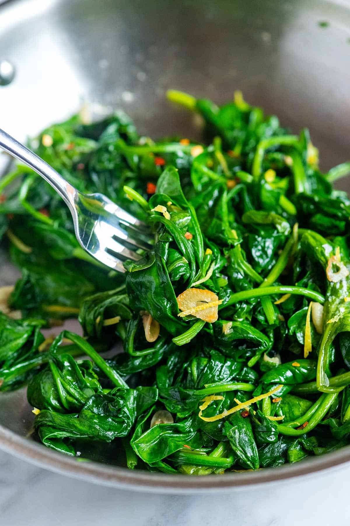 Spinach leaves cooked in a skillet with garlic and lemon