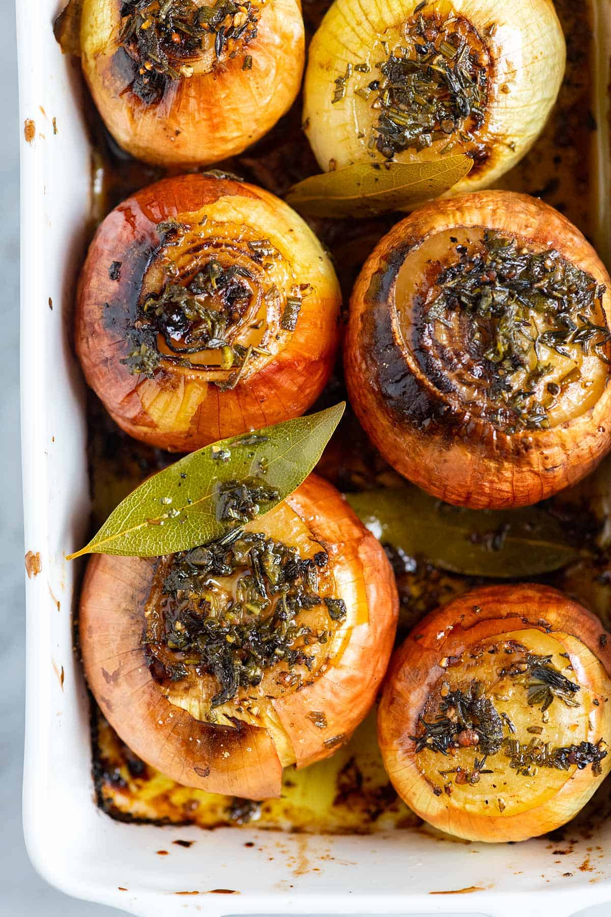 Whole roasted onions in a baking dish.