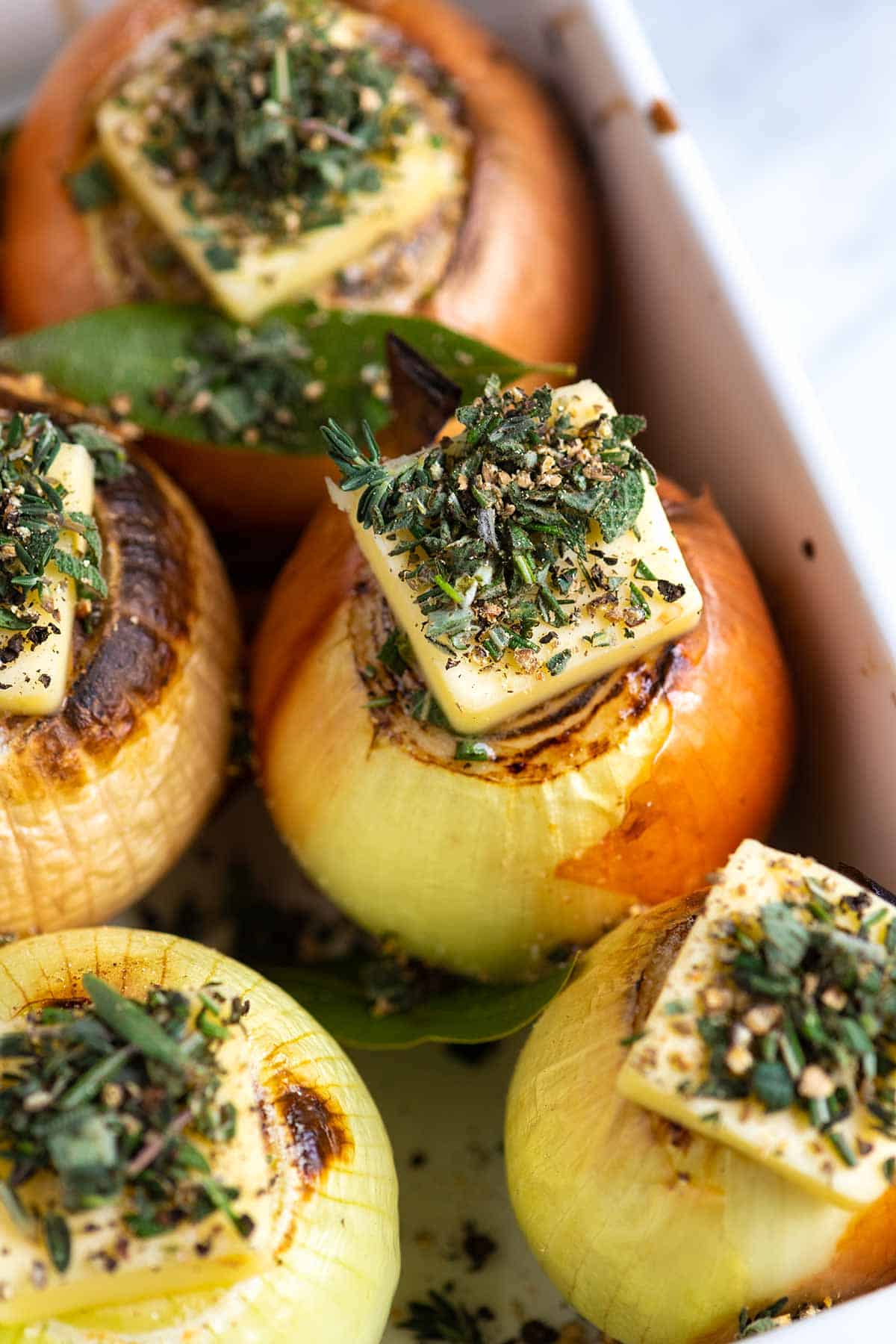 Onions that have butter and herbs on top. Ready to be roasted in the oven.