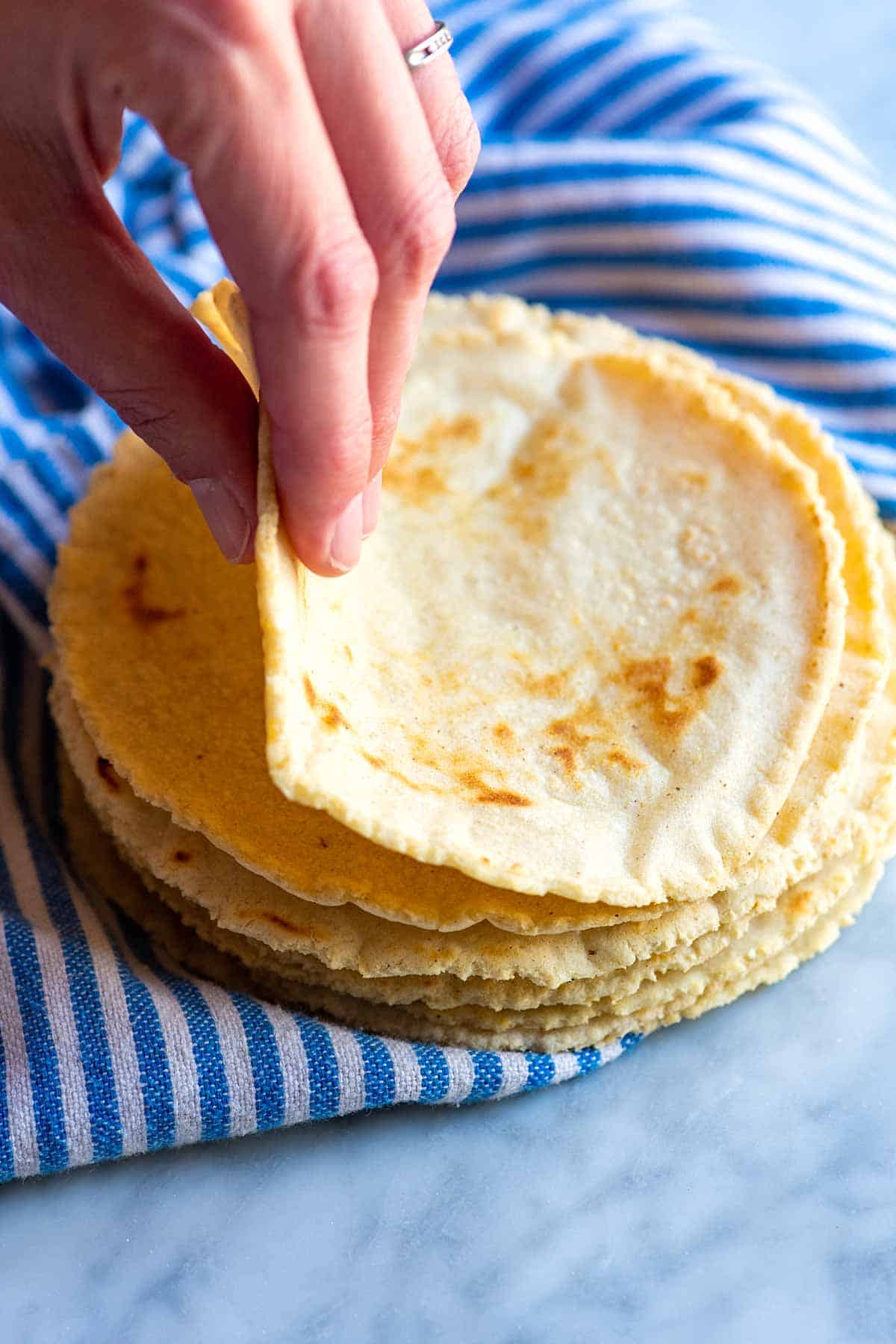 Taking from a stack of freshly made corn tortillas