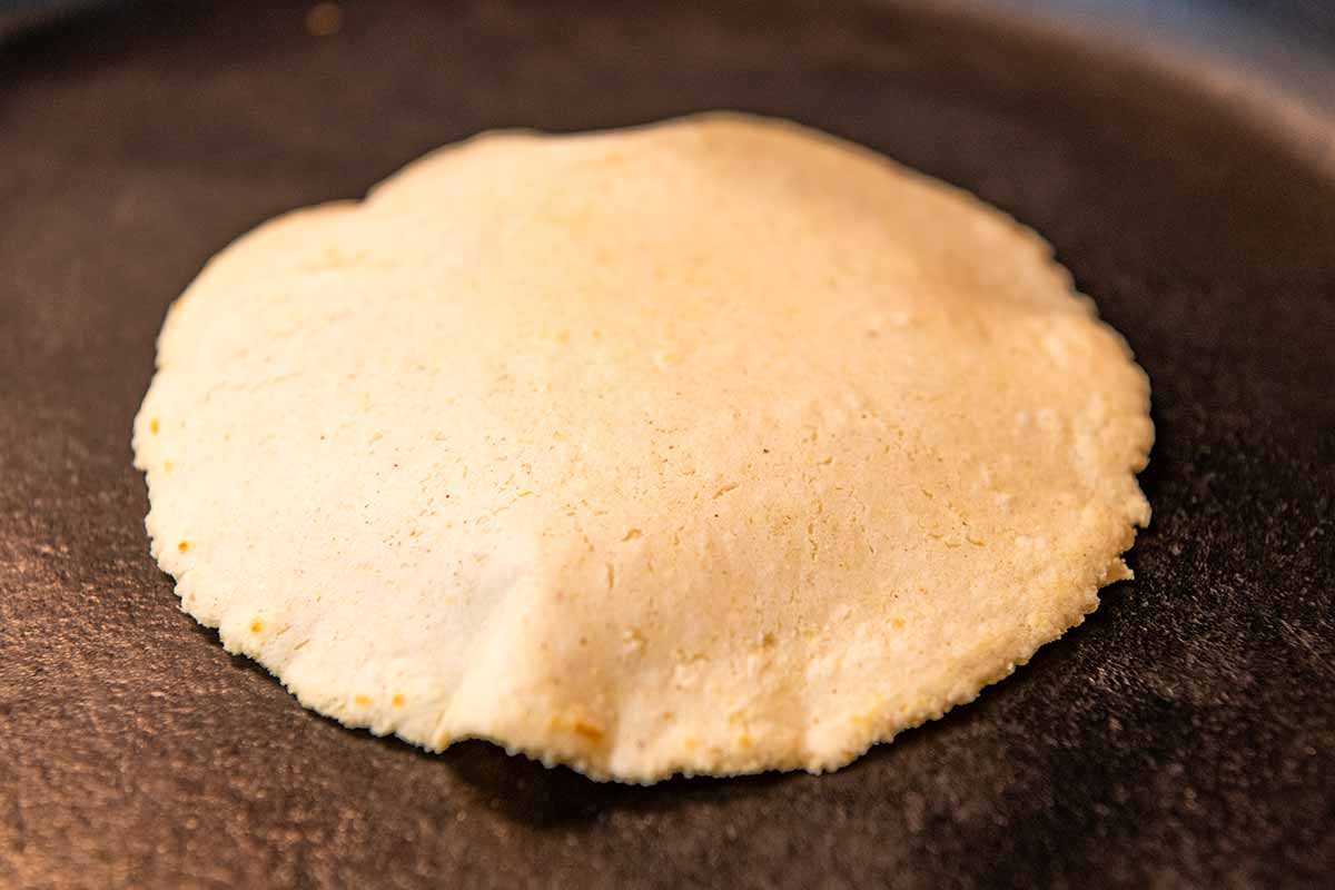 Cooking homemade corn tortillas in a hot skillet.