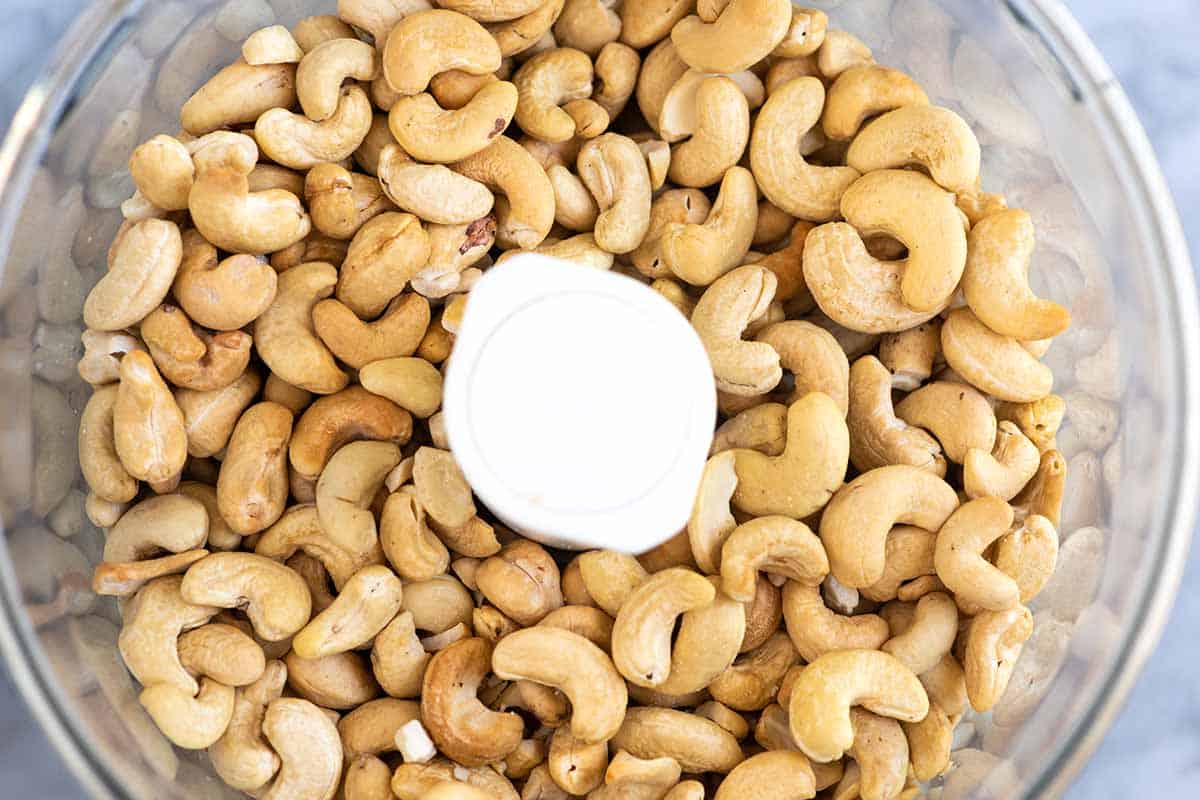 Roasted cashews in a food processor ready to be blended into cashew butter