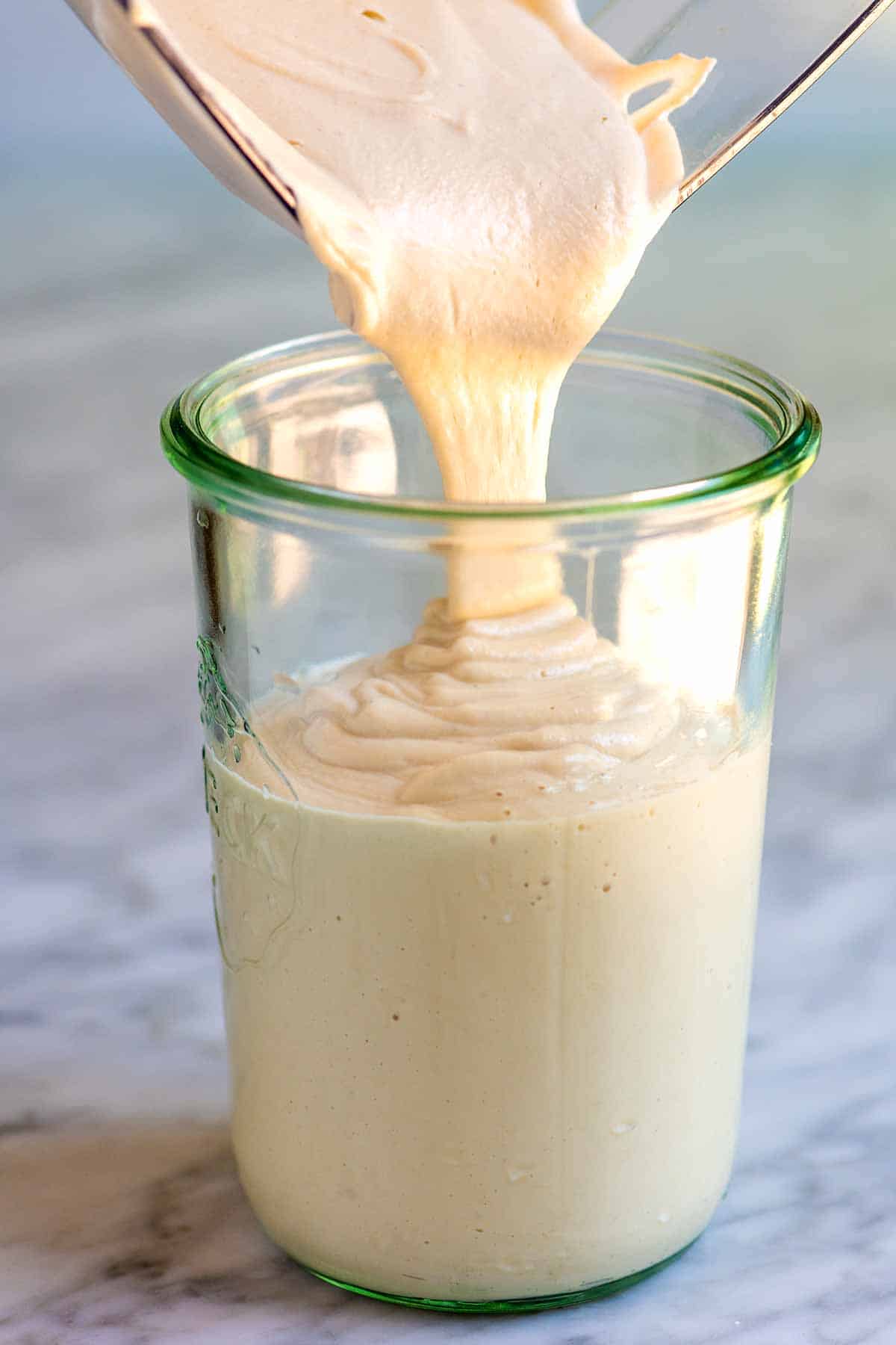 Pouring homemade cashew cream into a jar