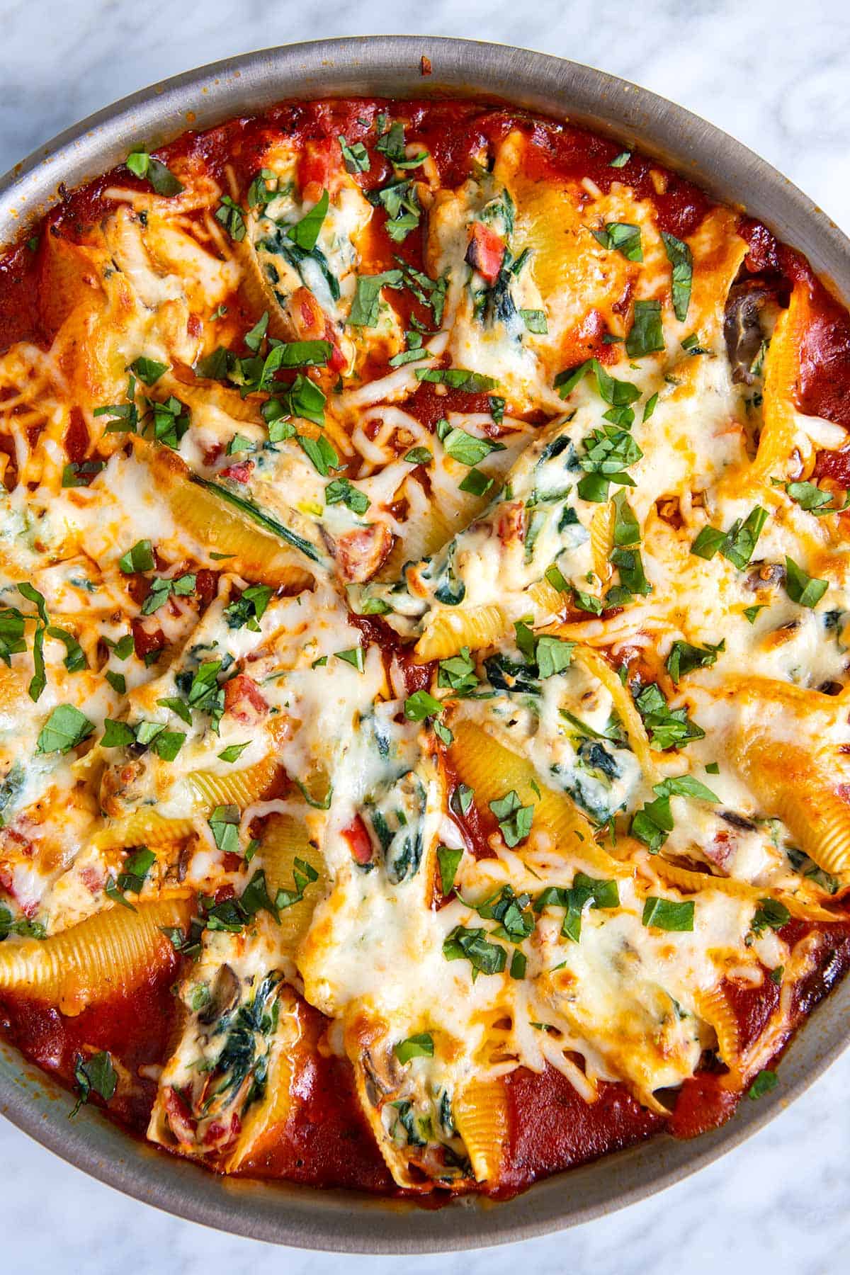 A skillet full of vegetable and cheese stuffed shells