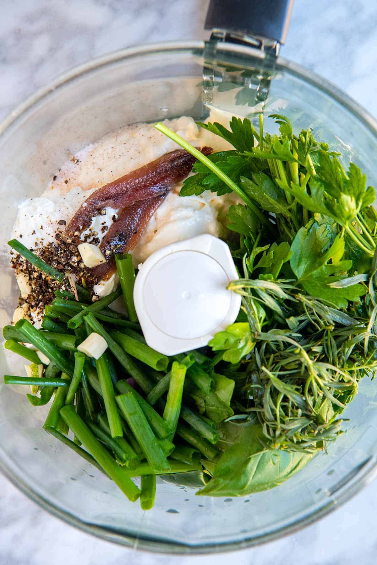 Green goddess dressing ingredients in the bowl of a food processor