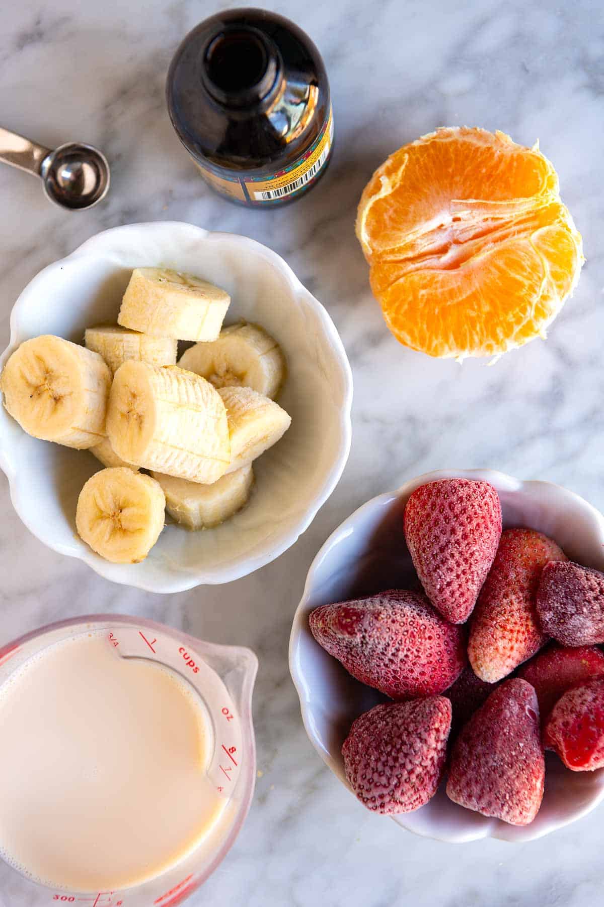 Ingredients for a Strawberry Smoothie (bananas, strawberries, orange, and milk)