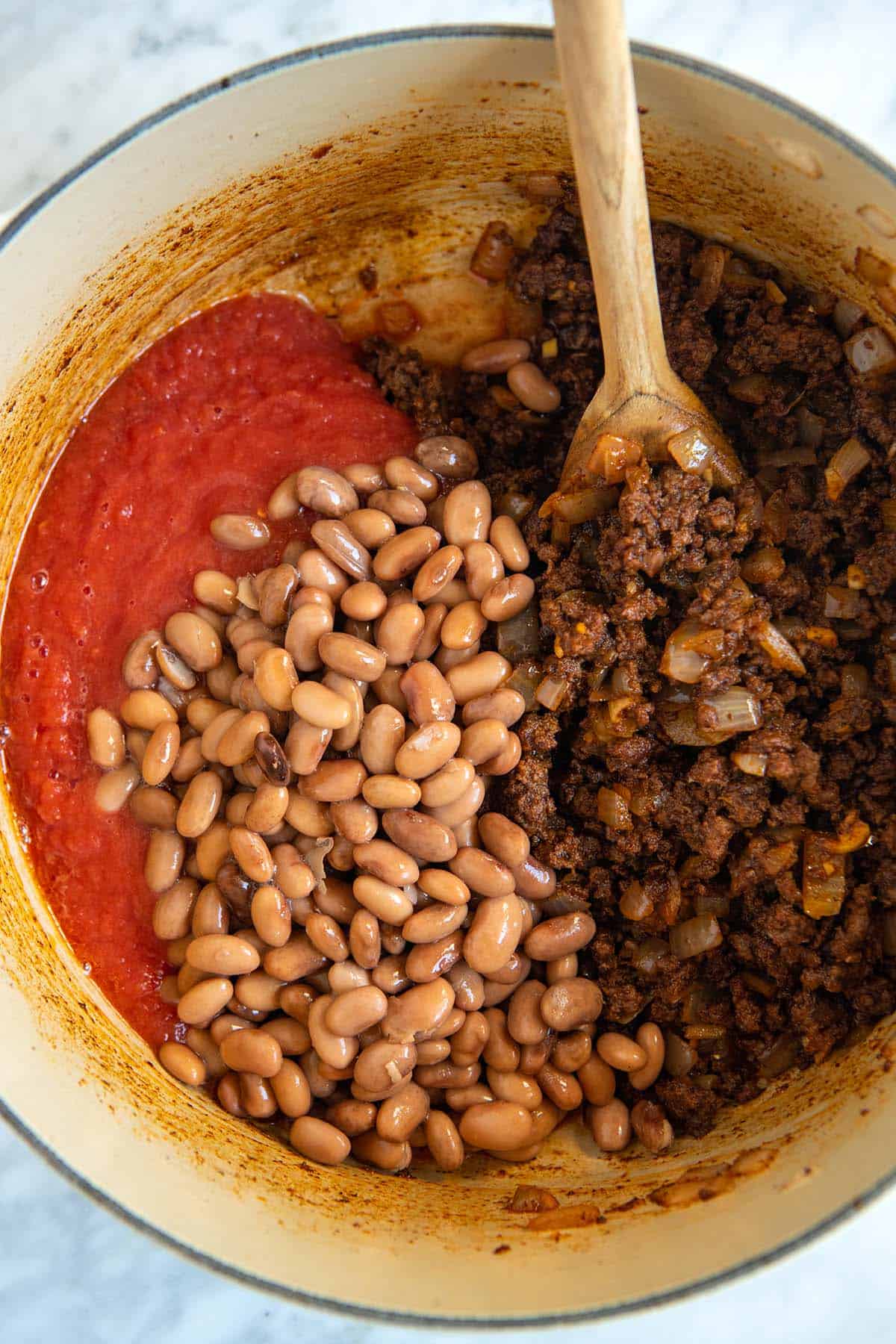 Adding tomatoes and beans to the chili