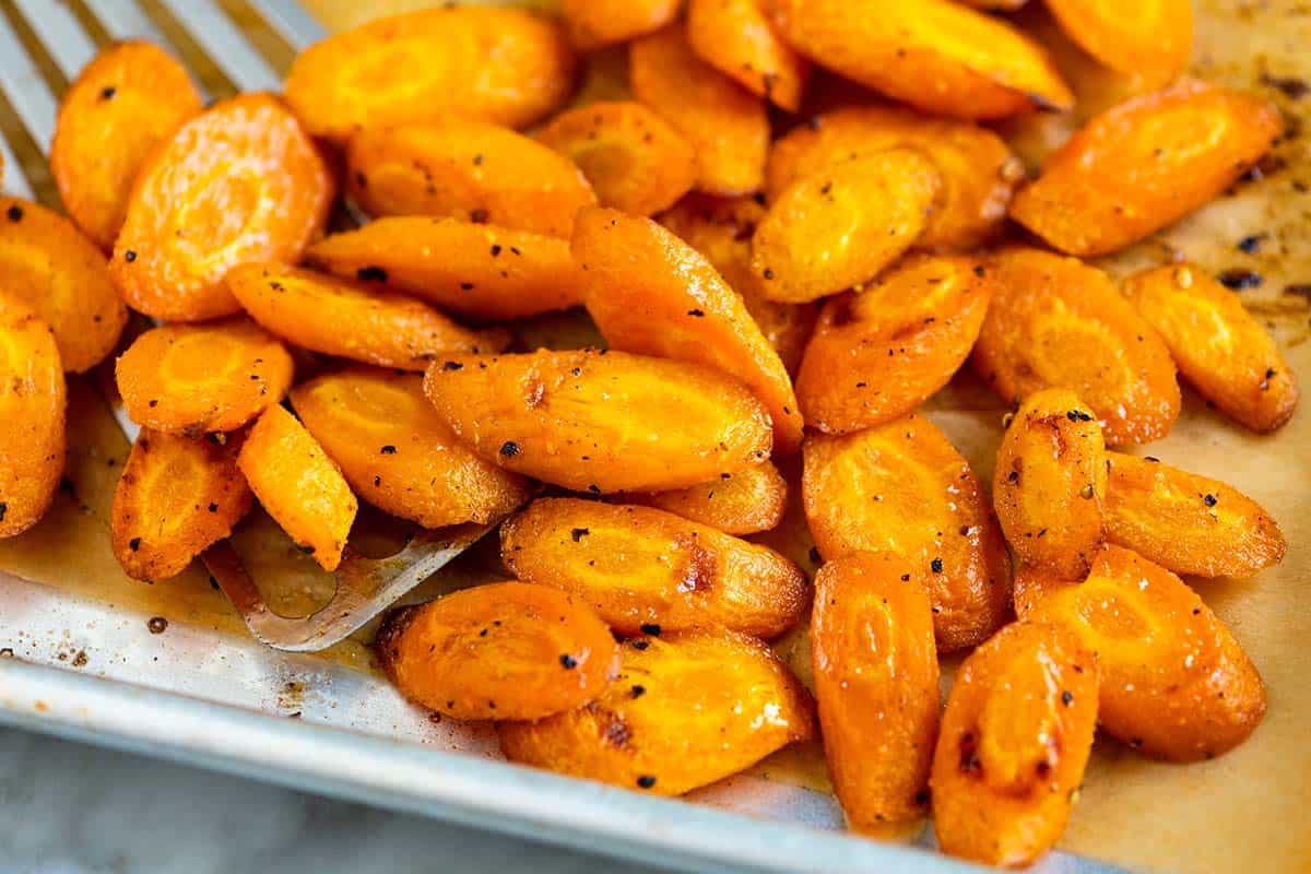 Close-up of roasted carrots on a baking sheet, with a mix of tender and caramelized edges.