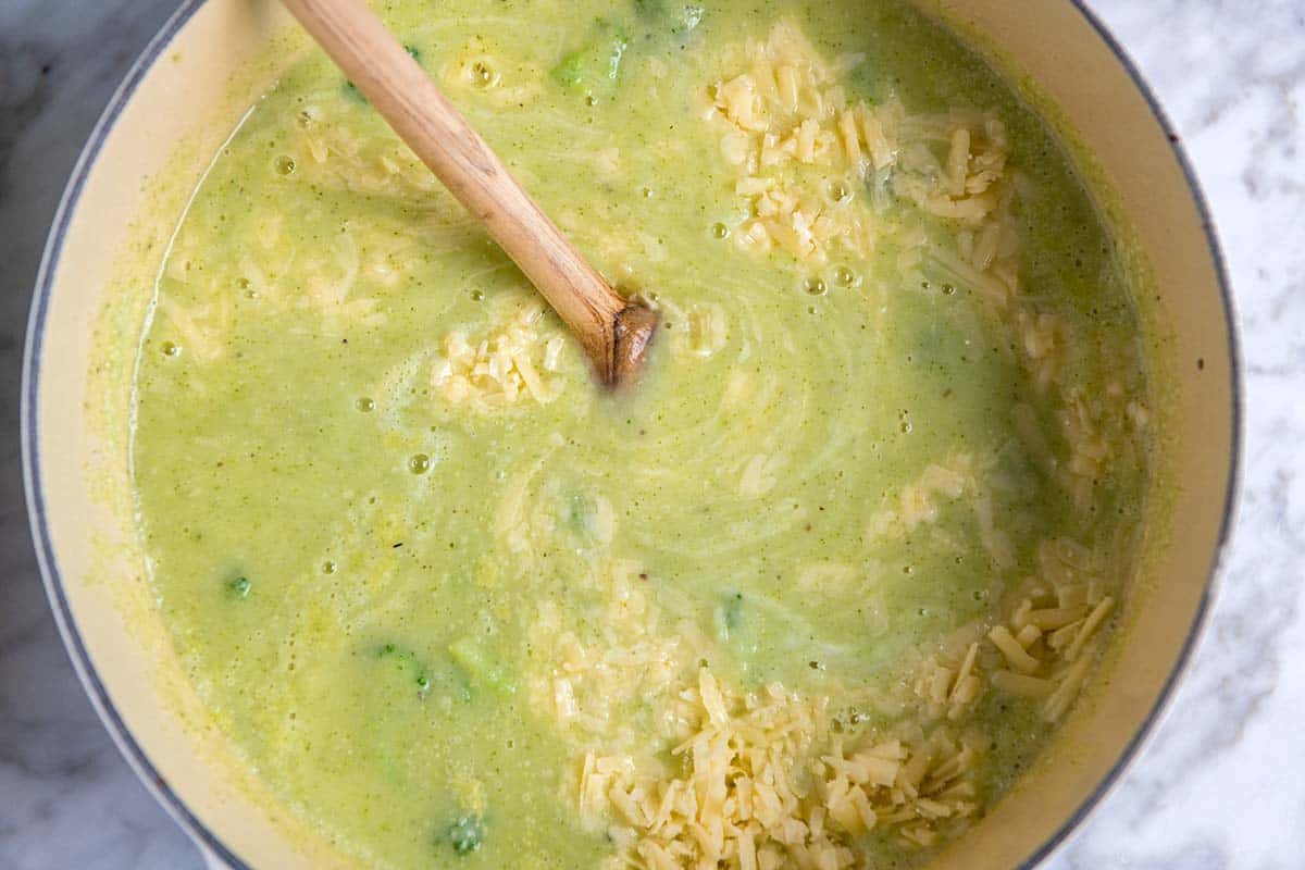 Stirring cheddar cheese into broccoli soup
