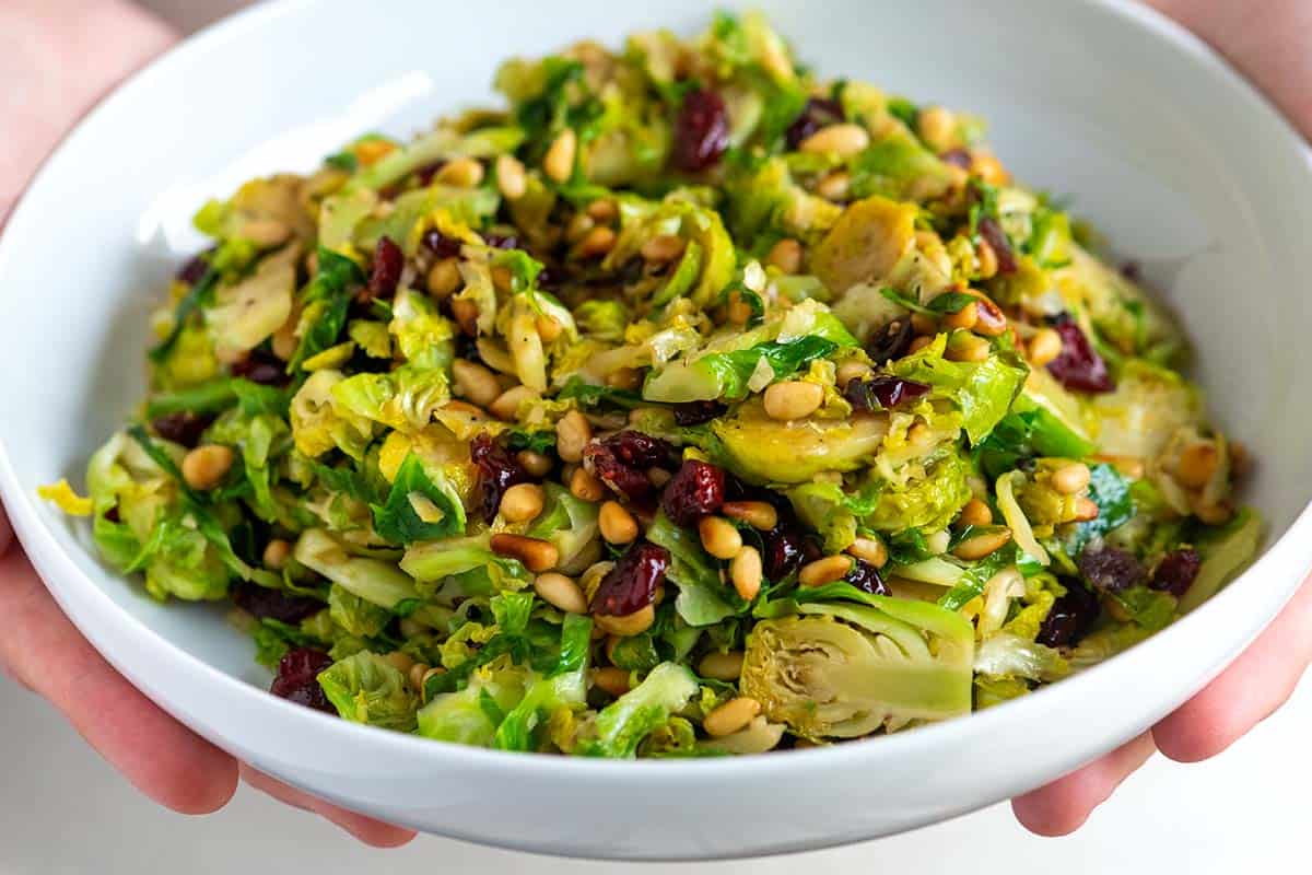 A Bowl of Sautéed Brussels Sprouts made with balsamic vinegar, cranberries, and pine nuts.