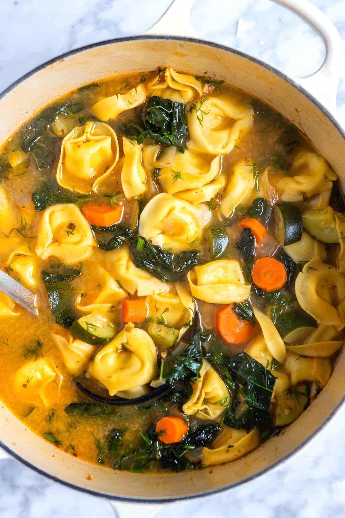 A pot of tortellini soup with kale