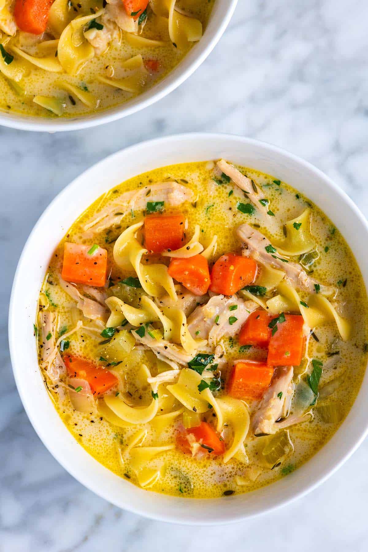 Two bowls of creamy chicken noodle soup