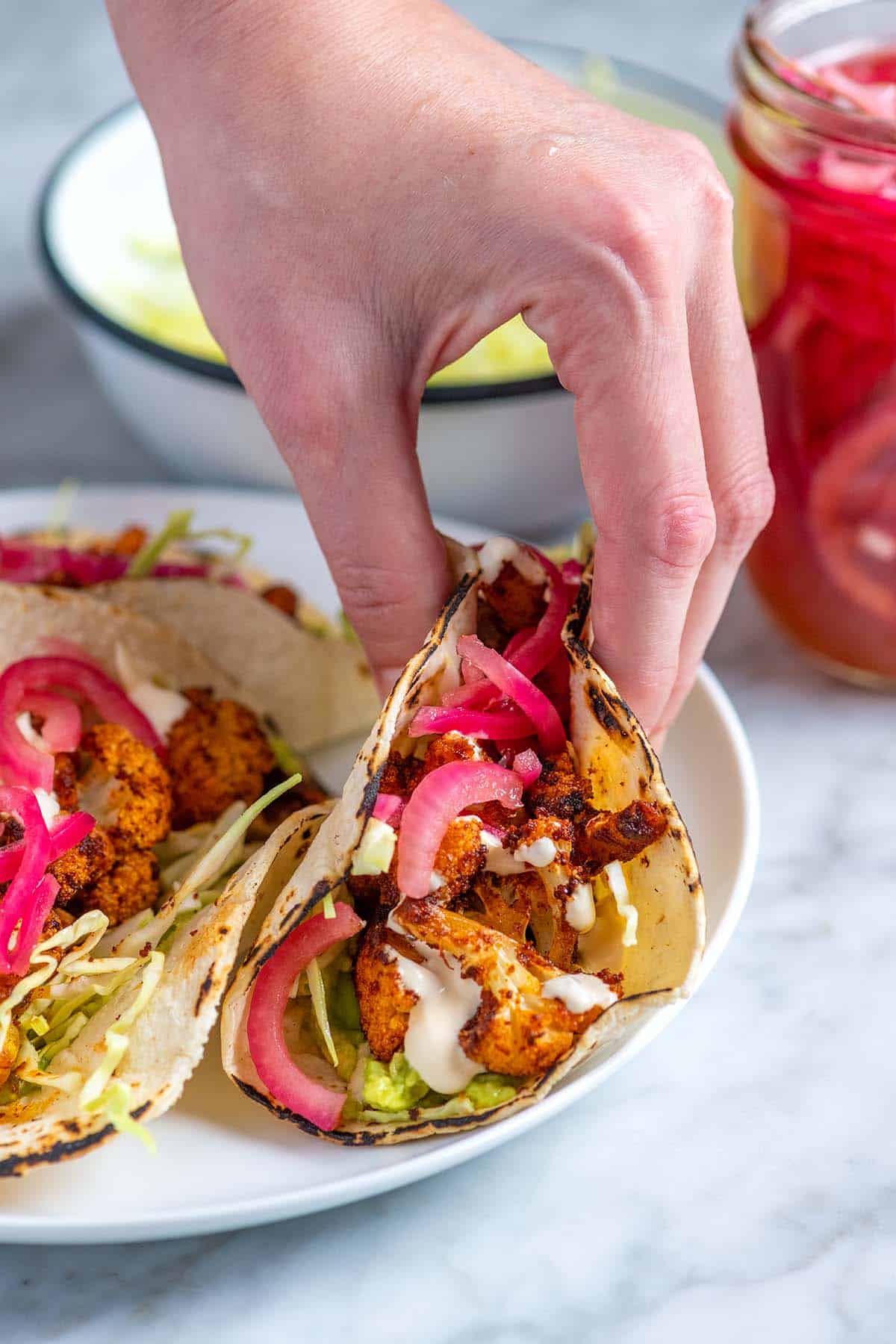 Grabbing a cauliflower taco with mashed avocado, roasted cauliflower, and pickled onions.