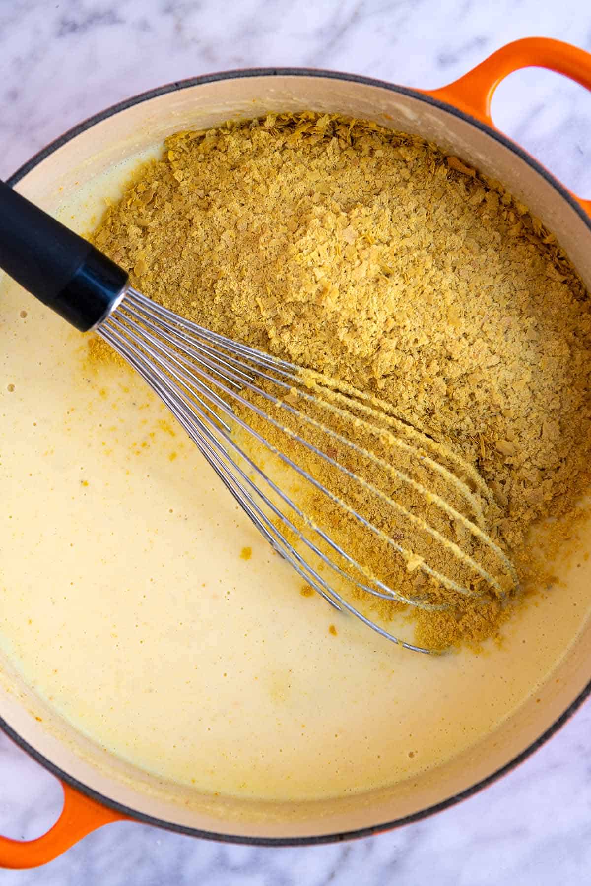 Stirring nutritional yeast into the vegan cheese sauce.