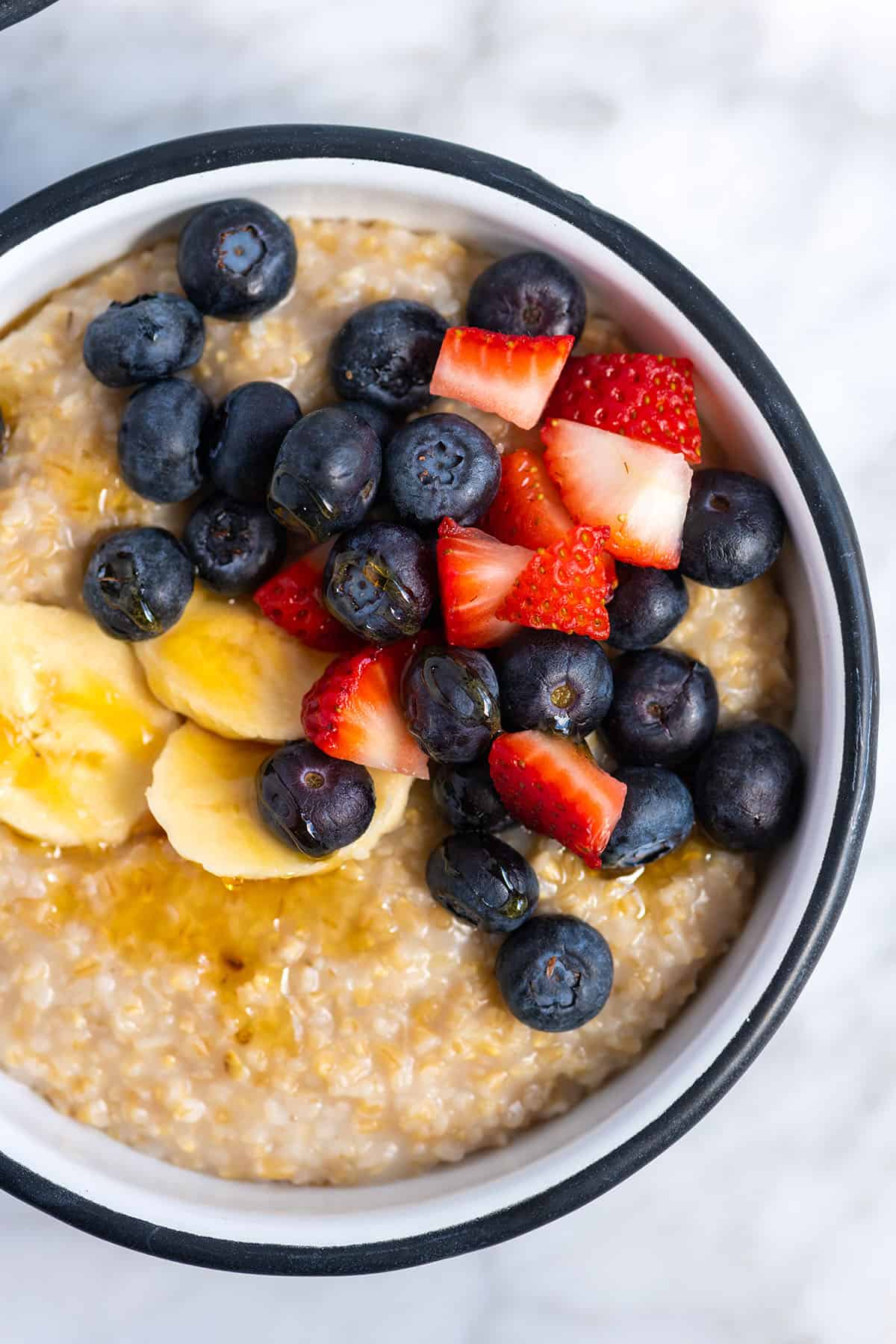 A bowl of steel cut oats with berries and honey on top