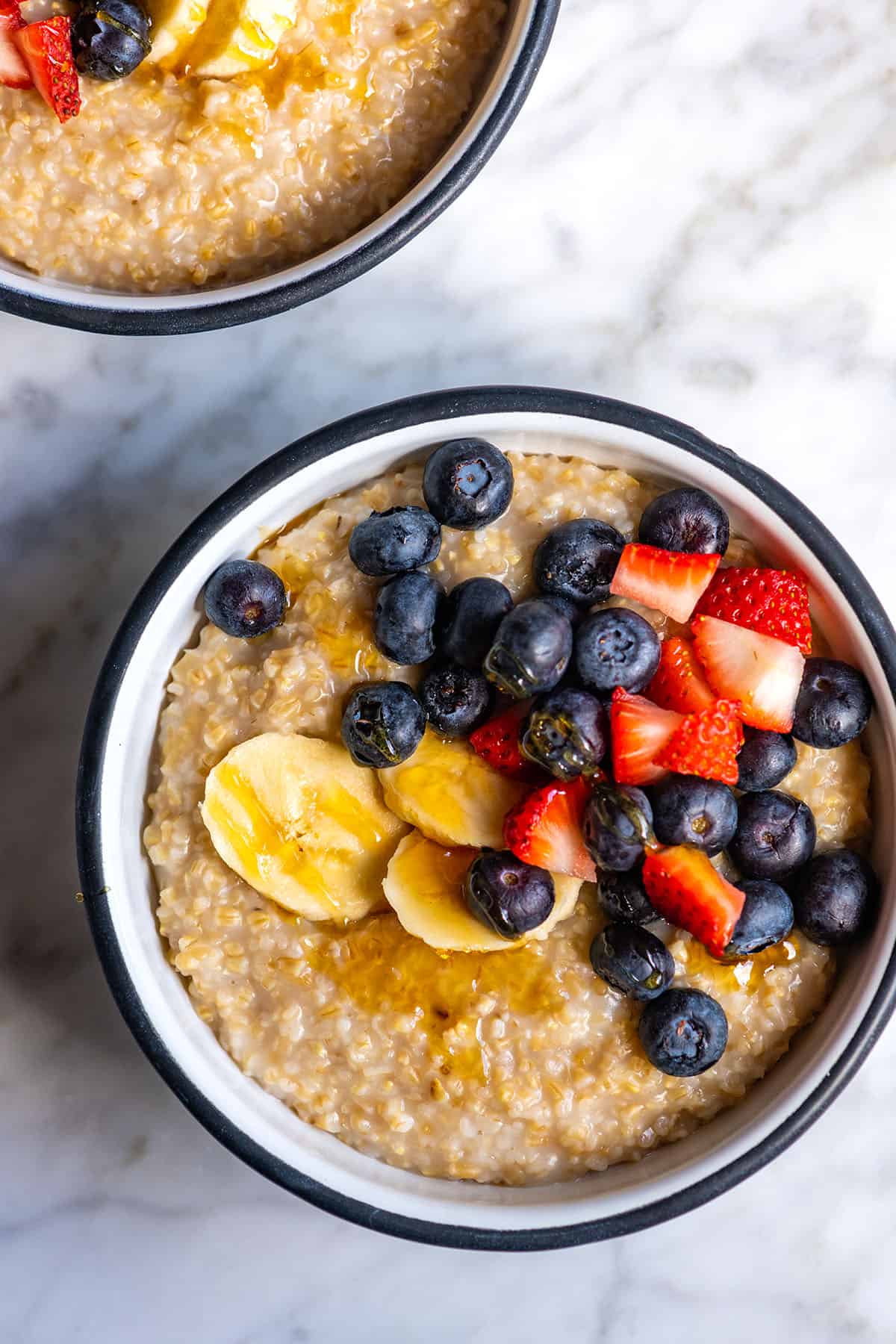 Bowls of creamy steel cut oats with berries and banana on top